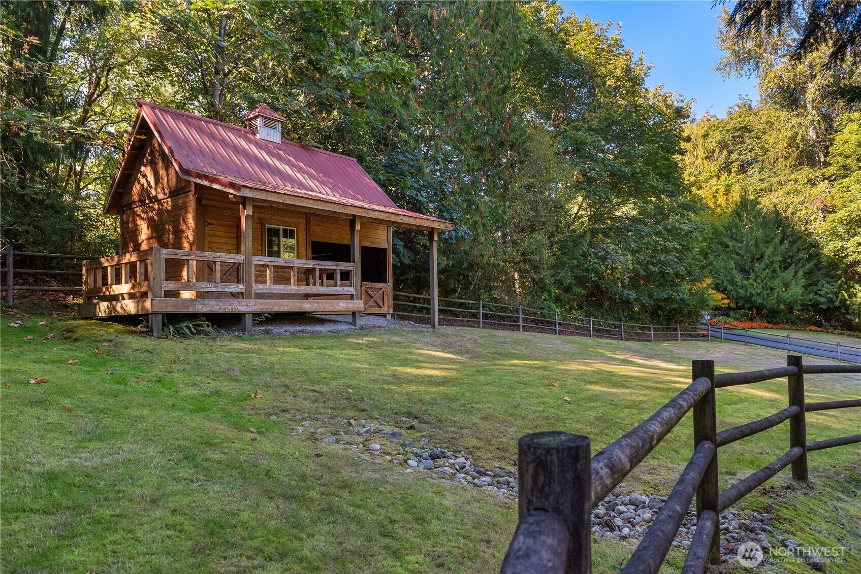 Wood barn strucutre with red metal roof and covered porch