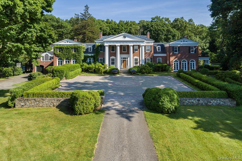 Set on 64 gated acres at one of the highest points in Bedford’s most exclusive estate area, this rare and historic brick Georgian mansion is approached by a half-mile drive lined with mature maples and fruit trees. Perched atop a private hill, the property commands sweeping western views toward the Catskill Mountains and enjoys a serene natural setting bordered in part by preserved parkland — ensuring lasting privacy and unspoiled beauty. Built in 1930 and owned by only three families in its history, the 10,000-square-foot residence exemplifies timeless Georgian architecture. Grandly scaled yet warmly livable, it features wide-board hardwood floors, six marble fireplaces, rich wood paneling, and soaring ceilings that reflect the craftsmanship of a bygone era. The home offers eight bedrooms and eight baths, including a refined primary suite with a marble bath, fireplace, and private balcony overlooking the grounds. Estate amenities include a charming guest house, a heated pool with cabana (fireplace, bar, and changing rooms), a tennis court, whole-property sound system, and full-property generator. Just 15 minutes to Bedford Village and 45 minutes from New York City, this is a once-in-a-generation opportunity to own one of Westchester’s great estates — a property of exceptional scale, provenance, and enduring appeal.