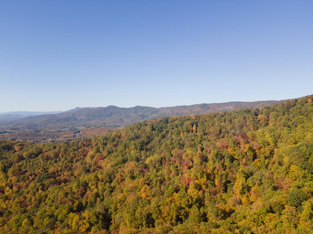 Wow—what a view. This exceptional 5-acre tract offers a truly rare vantage point with sweeping, long-range Piedmont views stretching 60+ miles, paired with stunning mountain sunsets that make every evening unforgettable. The setting is nothing short of surreal, and must be experienced in person to fully appreciate.  Whether you're looking to build your dream home or secure a smart long-term investment, this property checks all the boxes. With a recent perc test and well test already completed, much of the groundwork is in place to bring your vision to life. The combination of build-ready potential, limited inventory of comparable view properties, and strong regional demand makes this an attractive opportunity for both personal use and future value appreciation.  Located just minutes from the Blue Ridge Parkway, the property offers the perfect balance of privacy and accessibility—ideal for a full-time residence, second home, or vacation retreat. Community amenities include access to a stocked pond, a scenic waterfall, and a charming covered bridge with picnic area, creating an inviting environment for relaxation and recreation.  Conveniently positioned within reasonable driving distance to Winston-Salem, Blacksburg, Greensboro, and Charlotte, and less than 20 minutes to everyday essentials, you'll enjoy both seclusion and connectivity.  Properties with this combination of views, usability, and location are increasingly hard to find. If you've been waiting for the right opportunity, this is one you don't want to miss.