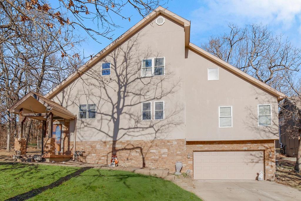 Welcome to this spacious 1.5-story home nestled in the heart of Lake Lotawana’s sought-after Mallard Bay. Situated on two generous lots and offering abundant parking space - a rare find at the lake - this property provides both privacy and flexibility. Surrounded by mature trees and featuring a fully fenced yard, you'll enjoy peaceful, wooded views from the back deck while embracing true lake lifestyle living. Step inside to a grand living area where the fireplace and beautiful mantel serve as a stunning focal point — ideal for cozy evenings or entertaining guests. The main level features three bedrooms, walk-in closets, two full bathrooms, and conveniently located laundry, offering the ease of main-floor living. Upstairs, you’ll find a private primary suite retreat along with an additional bedroom, loft area and expansive attic storage space. The finished lower level provides expansive additional living space, a full bath stubbed and ready for your finishing touches, and direct access to the two-car garage - perfect for a recreation room, hobby area, home gym or media space. With some updating, this home presents an incredible opportunity to personalize and create lasting lake memories. Enjoy easy access to a swim dock just across the street and take full advantage of everything Lake Lotawana has to offer — including Kansas City’s only waterfront restaurant accessible by boat. Hop on your golf cart and head just minutes away to the community park, tennis courts, local restaurants, and coffee shop. Life at Lake Lotawana means year-round activities — fishing tournaments, water skiing, sailing, kayaking, and vibrant community events. There’s always something happening in this one-of-a-kind lake community.