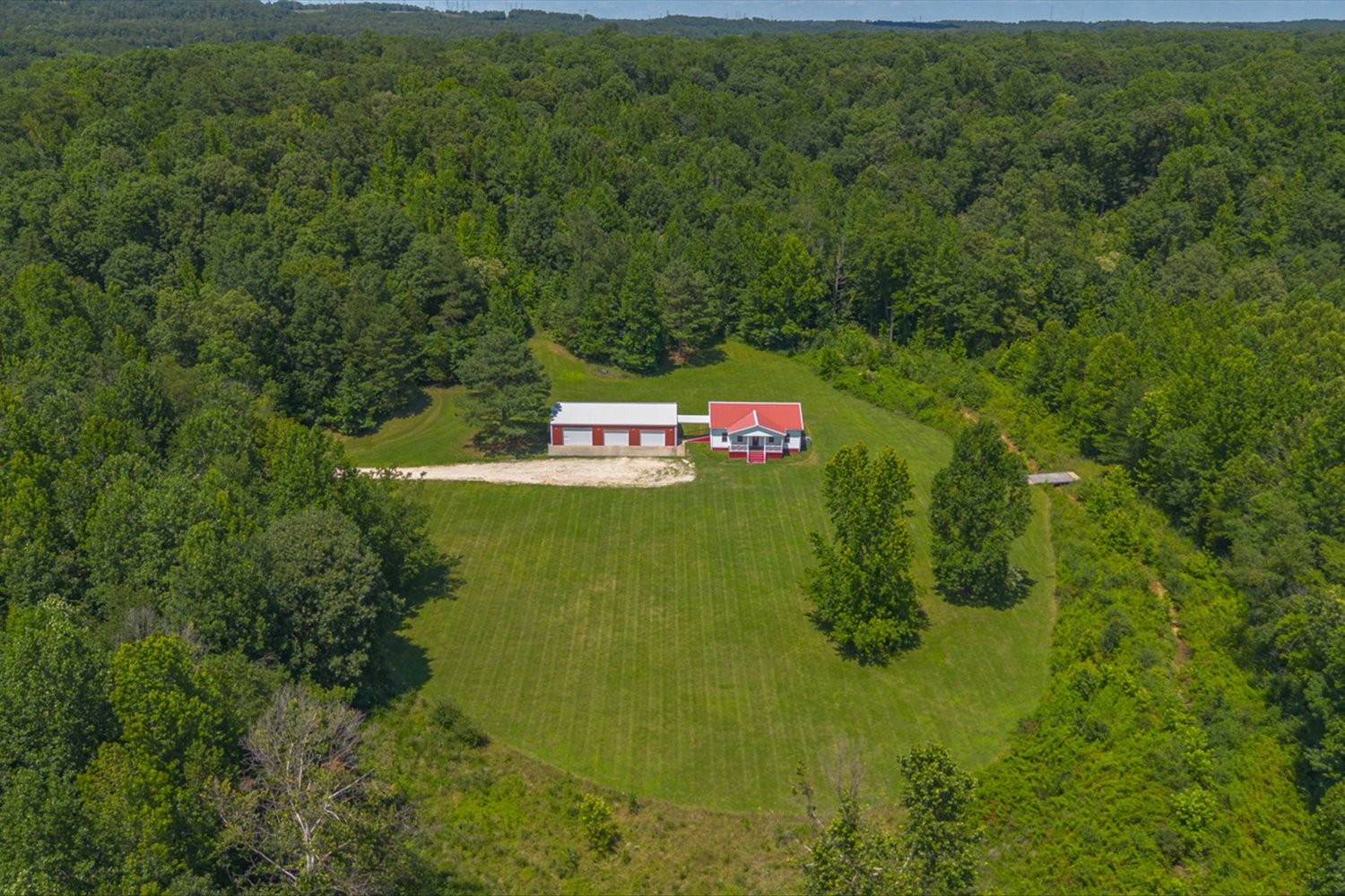 Wooded wonderland with over 28 acres and less than 2 minutes to the river.  A long, private gravel driveway leads you to your cottage nestled in a clearing in the woods. The home was custom built. High ceilings, 3/4" oak flooring, poplar ceiling, and lots of natural light. Primary bedroom, with double walk-in closets, has a luxury bath suite with walk-in shower with bench and a separate jet tub. Lots of closet space. Chef's kitchen with granite counter space ideal for entertaining, a separate dining area and a convenient, movable island. Very spacious and open home. Laundry room also serves as a huge pantry and home to the tankless hot water heater. Living room has gas hook-up for heater/contained fireplace. A massive detached garage with drainage can be used as a workshop, or a place for all your toys.  Workshop is plumbed for a full bath and the back has a full length covered porch perfect for  grilling and watching nature emerge from the woods. Wet weather creek on property with a bridge that leads to a magical grotto in the woods.  Truly breathtaking! Underground utilities, including gas. Drains under driveway. Natural spring on property. Greenbelt tax status.  Seller assumes there are trees for select cut on site. Loaded with wildlife. Ideal for a mini farm.  Close to town but a completely private compound. Property could be subdivided. Home warranty conveyed to buyer at closing. TDS internet. City owns front portion of lowlands that cannot be built on and provides driveway easement.  Gravel drive in excellent condition.Properties like this are very hard to find! Not in a flood plain. To verify any restrictions please contact the Humphreys County Recorder of Deeds. Property under heavy camera surveillance.