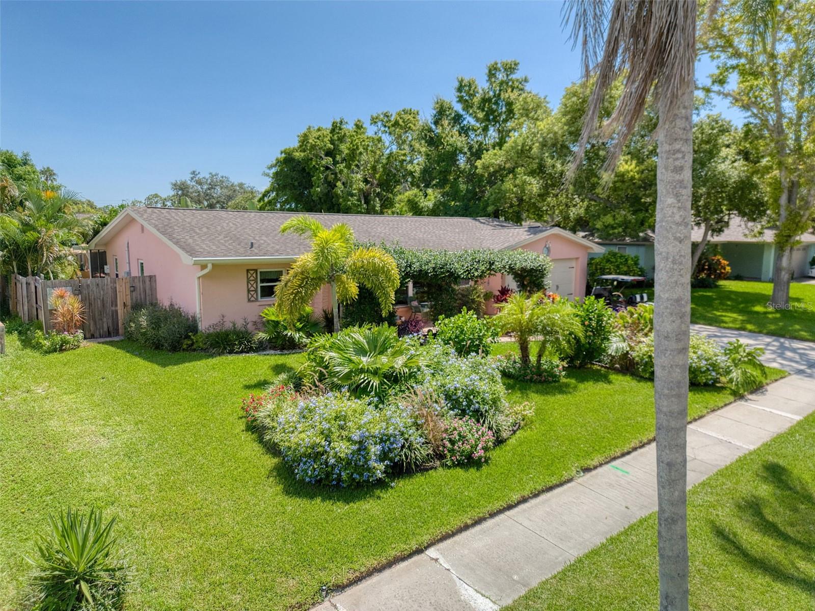 This tres chic 2 bedroom, 2 bath pool home sits gracefully on a beautifully landscaped oversized lot, NOT A FLOOD ZONE in the desirable Ranchwood Estates neighborhood in the delightful Dunedin golf cart area. Jump into your golf cart and venture downtown for dinner, or one of the many festivals or farmers markets. This charming home is tastefully renovated and boasts a living room, formal dining room and a large Florida room, 2 generous sized bedrooms both with ensuite bathrooms; and a spacious kitchen with exquisite granite countertops, 42" soft close white cabinetry and newer stainless steel appliances. The primary bedroom is split from the other bedroom and is a bright and spacious retreat with an ensuite bathroom.  The primary bathroom features a farmhouse sink with a marble countertop, and a generous shower/bath combo featuring a new cast iron Kohler tub. There is also a bathroom ensuite off the oversized 2nd bedroom that is tastefully renovated and features a beautiful large walk in shower.  The huge Oasis backyard is awesome!  It is so beautiful outside with stylish pavers and many native flowers and plants that attract birds and butterflies.  The jewel of this magnificent backyard is a heated salt water pool (2020).  The backyard is accessed from the light and bright Florida room, opening up on to a large paved patio with a gazebo for a seamless blend of indoor/outdoor entertainment living.  The spacious yard is fenced for privacy and pool safety. This home is move in ready with tasteful touches such as; neutral color tones, newer fans, modern light fixtures, porcelain wood look tile floors throughout this impeccably clean and welcoming home. This home also features newer rain gutters, hurricane impact windows (2019), newer flat roof (2022), main roof (2014), a/c (2020) and a newer hurricane garage door. There is plenty of natural light and room to grow in this well laid out open floor plan. This layout allows the ability to covert the formal dining room into an office or 3rd bedroom.  Couple this with excellent schools and close to shops, airports, beaches and all that fabulous downtown Dunedin has to offer and you have the quintessential Florida lifestyle home.