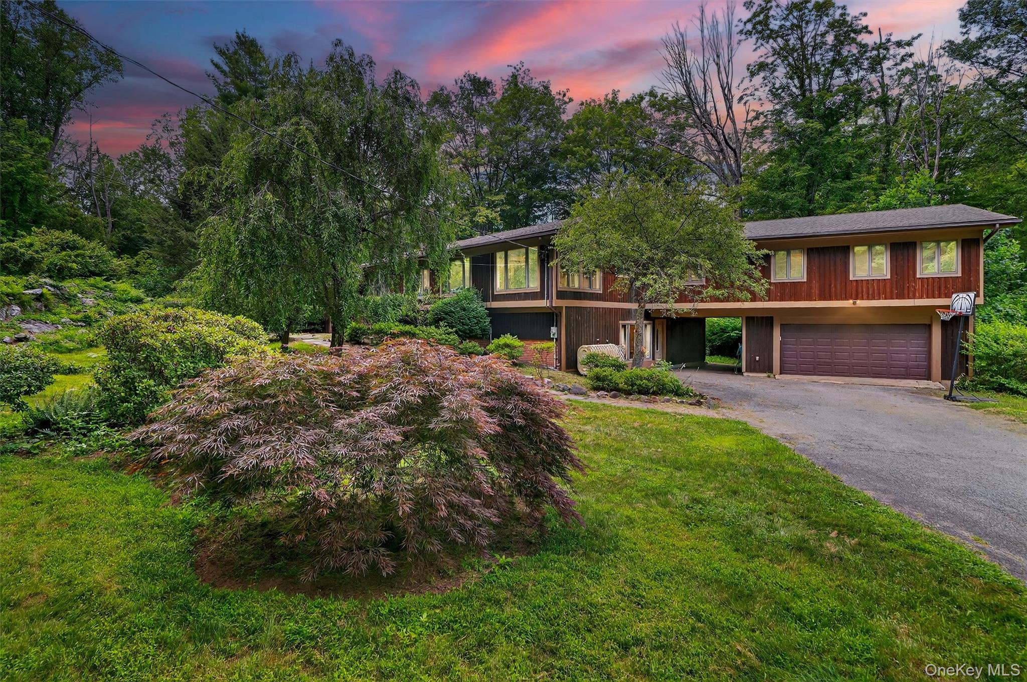 Spacious, private, and filled with possibility, this split-level contemporary with four bedrooms and four baths offers nearly 5,000 square feet of living space. Built in 1969 and thoughtfully expanded in 2011, it blends generous proportions with a versatile layout. Tucked away on almost four wooded acres, it offers exceptional privacy with all the room you need to live, work, and entertain.
The main level is defined by soaring vaulted ceilings, walls of glass, and a striking two-sided fireplace linking the living and dining rooms. The generously sized kitchen flows into both the dining room and screened-in patio, creating a natural connection for everyday living and entertaining.
A few steps down, the lower level centers on a welcoming family room with its own fireplace and a well-appointed wet bar. The adjoining spaces on this level offer endless flexibility for a home gym, media room, an additional den or office—all tailored to your lifestyle.
The upper level flows beautifully, beginning with a spacious primary suite featuring a jetted tub, oversized tiled shower, and dual walk-in closets. A private guest suite with its own bath and sliders, two additional bedrooms, a hall bath, and a dedicated laundry room complete the accommodations. An expansive open area on this level provides flexible, fun square footage, ideally suited for a game room or creative retreat, along with another open space perfectly suited for a home office.
Step outside, and the property truly unfolds—four serene acres of natural beauty invite the creation of the compound you envision. Imagine a pool, a sport court, or simply curated gardens and outdoor living spaces, all framed by complete privacy. Well-proportioned and solidly built, the home is ready for thoughtful updates, allowing you to refine select finishes and details to your own taste. Its rare combination of seclusion and convenience—just minutes from the charm of Bedford Village and the sophistication of Greenwich—makes this an exceptional opportunity to invest in a property with both presence and promise.
Welcome home.