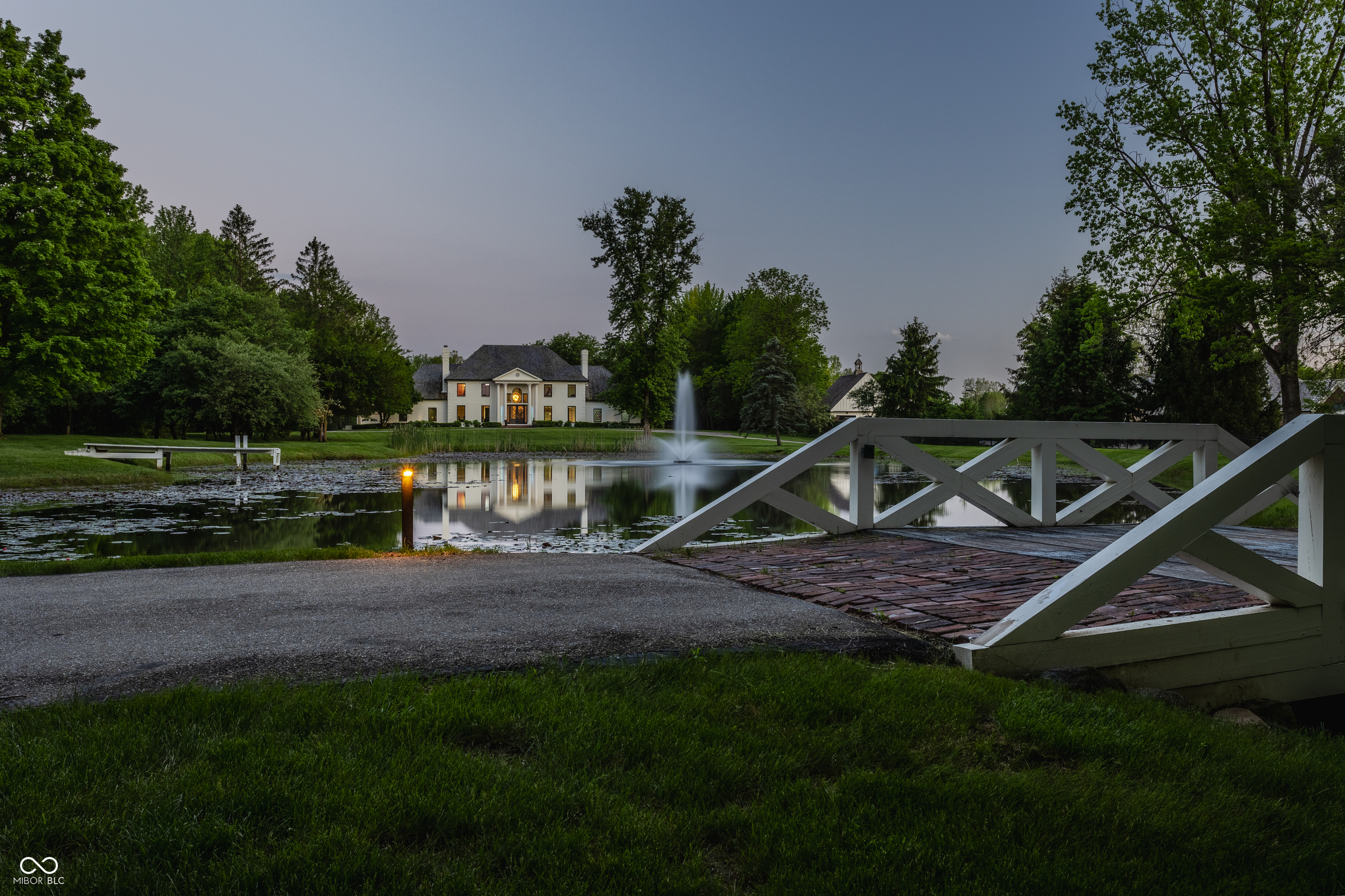 Welcome to your own private oasis in Zionsville. A gated drive and charming bridge set the tone as you arrive at this breathtaking 8-acre estate, nestled among mature trees and overlooking a serene pond with a fountain. This extraordinary property boasts a gunite pool, tennis court, carriage house, and space for a future equestrian center. This completely renovated 6-bedroom home showcases exceptional craftsmanship with elegant archways, five fireplaces, a dramatic two-story entry, and generous room sizes. Multiple sets of doors offer a seamless connection to the spectacular outdoor living areas. Thoughtfully designed for everyday living, the home features a stylish mudroom complete with a dog shower, and a spacious second-floor laundry room for added convenience, as well as a new, outdoor invisible fence. Additional highlights include a 3-car attached garage and detached garages beneath the carriage house. This is truly a rare opportunity to own a private estate that combines refined living with resort-style amenities!