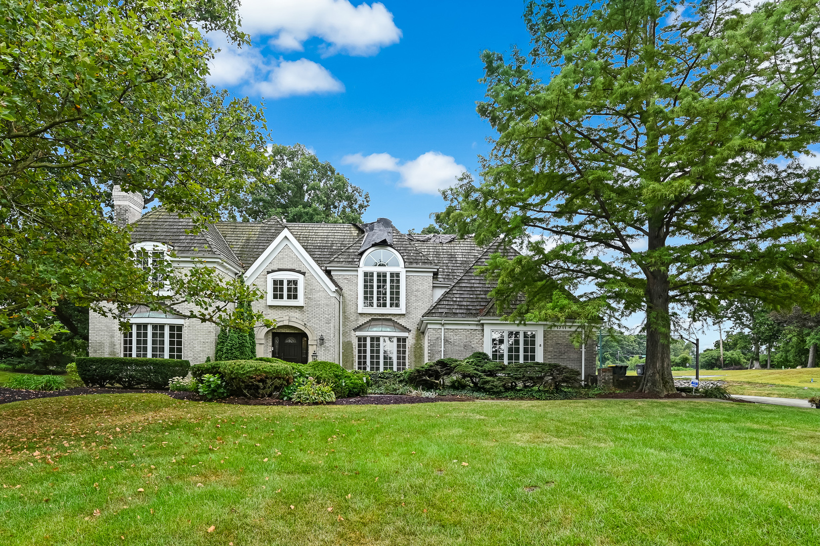 Tucked away on a sprawling .79-acre lot within the prestigious Midwest Club, this property presents a rare opportunity to either renovate the existing structure or build the custom estate of your dreams. The current home features a thoughtful layout with four bedrooms-each with its own ensuite bath-along with formal living and dining rooms, a first floor office, a three-car attached garage, and a massive unfinished lower level ready for your personal touch. Living in The Midwest Club is about more than just a home; it's about a lifestyle defined by luxury and ease. The community is anchored by a clubhouse, an outdoor swimming pool and hot tub, tennis and pickleball courts, and a playground. From the moment you pass through the majestic entry-complete with reclaimed Chicago pavers and an English cottage-style gatehouse-the attention to detail is clear. Seven scenic ponds, seasonal waterfalls, and meticulously maintained green spaces create a stunning backdrop for daily life, while the on-site management team fosters a vibrant community spirit through seasonal activities and holiday gatherings. Privacy and convenience go hand-in-hand here. The main entrance is managed by 24-hour on-site security, providing total peace of mind. Plus, the location is hard to beat, offering quick access to major expressways, airports, premier shopping, and an incredible variety of fine dining. Adding to the appeal, this property is situated within the highly acclaimed Butler Elementary and Hinsdale Central High School districts. Whether you're looking to polish a diamond in the rough or start fresh on a premier lot, this is your chance to join one of the area's most sought-after communities.