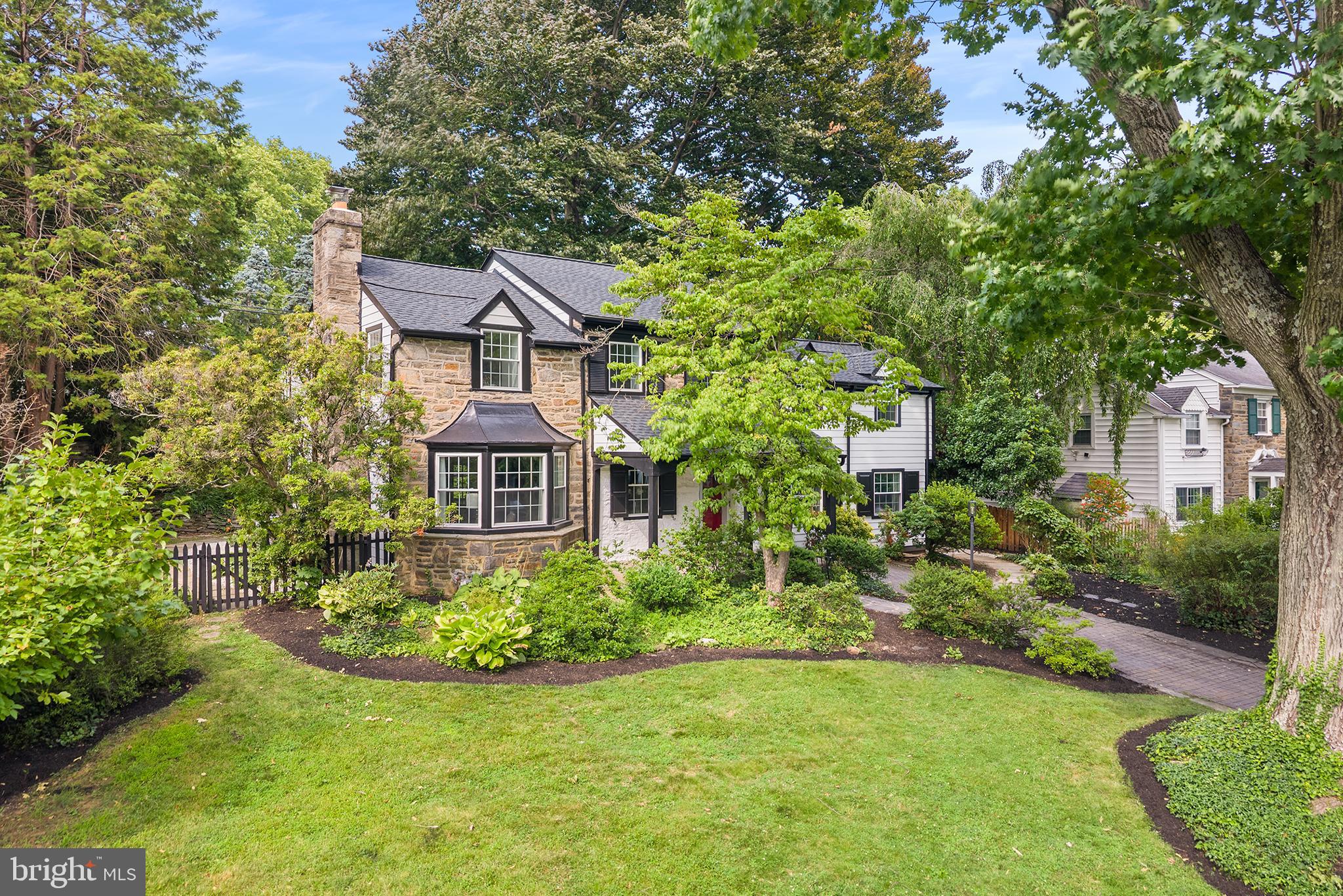 Perfectly blending timeless Main Line charm with thoughtfully curated modern updates, this exceptional stone Colonial is nestled on a picturesque, tree-lined street in the heart of Wynnewood's coveted Penn Wynne neighborhood. Beautifully reimagined with designer finishes throughout, this home offers the perfect balance of classic architecture and contemporary living. The heart of the home is a stunning chef's kitchen designed for both everyday living and effortless entertaining, featuring elegant stone countertops, a designer range hood, a premium GE Café suite of appliances, and a beautifully appointed butler's pantry complete with additional storage and a built-in wine refrigerator. Just beyond, the formal dining room is flooded with natural light from dramatic floor-to-ceiling windows that frame peaceful views of the professionally landscaped rear yard, creating an inviting setting for everything from intimate dinners to holiday gatherings. The home's living spaces are equally impressive. A gracious formal living room offers a warm and sophisticated retreat centered around a wood-burning fireplace with a striking new stone mantel, while a separate, cozy den features custom built-in shelving and a media console, making it the perfect space to unwind. Tucked just beyond the den is a versatile bonus room ideally suited as a home office, playroom, or quiet reading room. Upstairs, you'll find 5 generously sized bedrooms and 3 full bathrooms, including a bright and serene primary suite positioned on the corner of the home to take advantage of multiple window exposures and abundant natural light. The spacious suite features a beautifully renovated ensuite bath with a tiled walk-in shower, thoughtful his-and-hers storage solutions, and a peaceful atmosphere that feels like a private retreat. In addition to the 5 bedrooms, you'll find a flex space on the second floor, previously used as an art studio, offers endless possibilities as a nursery, yoga or wellness room, second home office, creative studio, or private retreat. Outside, the beautifully landscaped backyard serves as a true extension of the home, offering mature plantings, elegant stone hardscaping, and exceptional privacy—an ideal backdrop for outdoor entertaining or peaceful evenings at home. Beyond its beautiful finishes, this home has been comprehensively updated for peace of mind with a NEW ROOF, ALL-NEW HVAC system, new ELECTRICAL, new PLUMBING, and new WINDOWS, offering the confidence of modern infrastructure while preserving the timeless character that makes Main Line homes so desirable. Located within the award-winning Lower Merion School District, this home provides access to Penn Wynne Elementary, Black Rock Middle School, and Lower Merion High School. Enjoy the convenience of being just minutes from Suburban Square, downtown Ardmore, Wynnewood Shopping Center, Whole Foods, Trader Joe's, neighborhood favorites including Sabrina's Café, Char & Stave, and Delice et Chocolat, as well as SEPTA Regional Rail for an easy commute to Center City Philadelphia. Combining beautifully updated interiors, flexible living spaces, and one of the Main Line's most sought-after locations, this is a rare opportunity to own a truly special home in Penn Wynne.