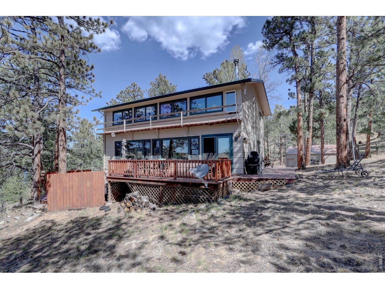 Imagine waking up every morning, grabbing a coffee and heading out to the wrap around deck where the deer bid you good morning as you gaze out onto Pinewood Reservoir through a canopy of ponderosa pines and aspens with the Rocky Mountains stretched out on the horizon. That is not a vacation. That is your life here at this mountain sanctuary.This is the kind of place where you slow down and actually feel it. Relaxing on the deck as mist lifts off the water, soaking in a hot tub under the stars at night, and spending weekends the way they should be spent, completely unplugged and surrounded by nature and wildlife. Explore the outdoors right at your doorstep with the lake just yards away. Hop in a kayak, cast your fishing pole, and admire the sun as it rises over the mountains. No matter what your day brings it is a wonderful feeling to return to your home laced with knotty pine accents, heaps of natural light, and breathtaking views of the lake, mountains and endless blue skies. Three things you will love. First, a great room offering soaring ceilings, hand-hewn log posts and beams, wall of windows framing incredible views of Pinewood Reservoir, and a river rock wood-burning stove that makes every evening feel like an event. Second, effortless year-round outdoor living. Multiple decks, including a main entertaining deck and lower hot tub deck, putting those lake and mountain views right at your fingertips. Step outside and it is right there, the water, the mountains, the open sky, all of it. Third, plenty of room for everyone and everything. Open main level including a primary suite, huge kitchen and great room, the upper loft with log railings, the expansive lower level recreation room, media area, and fitness space, plus a detached oversized garage and workshop means this home lives way bigger than it looks. If you have been waiting for a retreat that actually feels like one, this is your moment. Plus the SELLER IS MOTIVATED!!