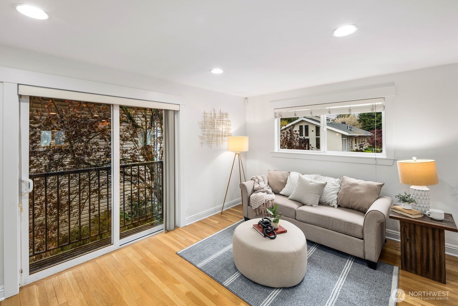 Spacious and flexible end-unit townhome in the heart of Greenwood that meets modern living. Tucked within a 3-unit community with no HOA, this home offers a perfect blend of privacy and convenience. The corner position brings in exceptional natural light through large windows while maintaining a quiet, protected feel. A wider-than-typical layout, tall ceilings, and open spaces create an airy, comfortable flow you don’t often find in Seattle townhomes. The entry level includes a flex bedroom / office and full bath with its own secure back entrance—ideal for guests, work-from-home, or rental potential. Off the entry level bed you'll find a unique fully-fenced yard with code-equipped access that adds usable outdoor space without sacrificing privacy. The second level is dialed—featuring hardwood floors throughout the open concept living, kitchen, and dining spaces, plus a well-placed powder room off the living area. The kitchen has a gas range, ample cabinetry, bar seating, and great prep space for daily living or hosting. On the 3rd and final level, you'll find the primary suite with a double vanity en-suite and strong natural light between the mature landscaping shading the Juliet balcony. Fresh interior paint and new carpet make it truly move-in ready. Dedicated 1-car off-street parking right outside the front door provides everyday convenience. Steps to transit and minutes to the lightrail. Simple commute to DT, the Eastside, and all Seattle has to offer. Don't miss it!