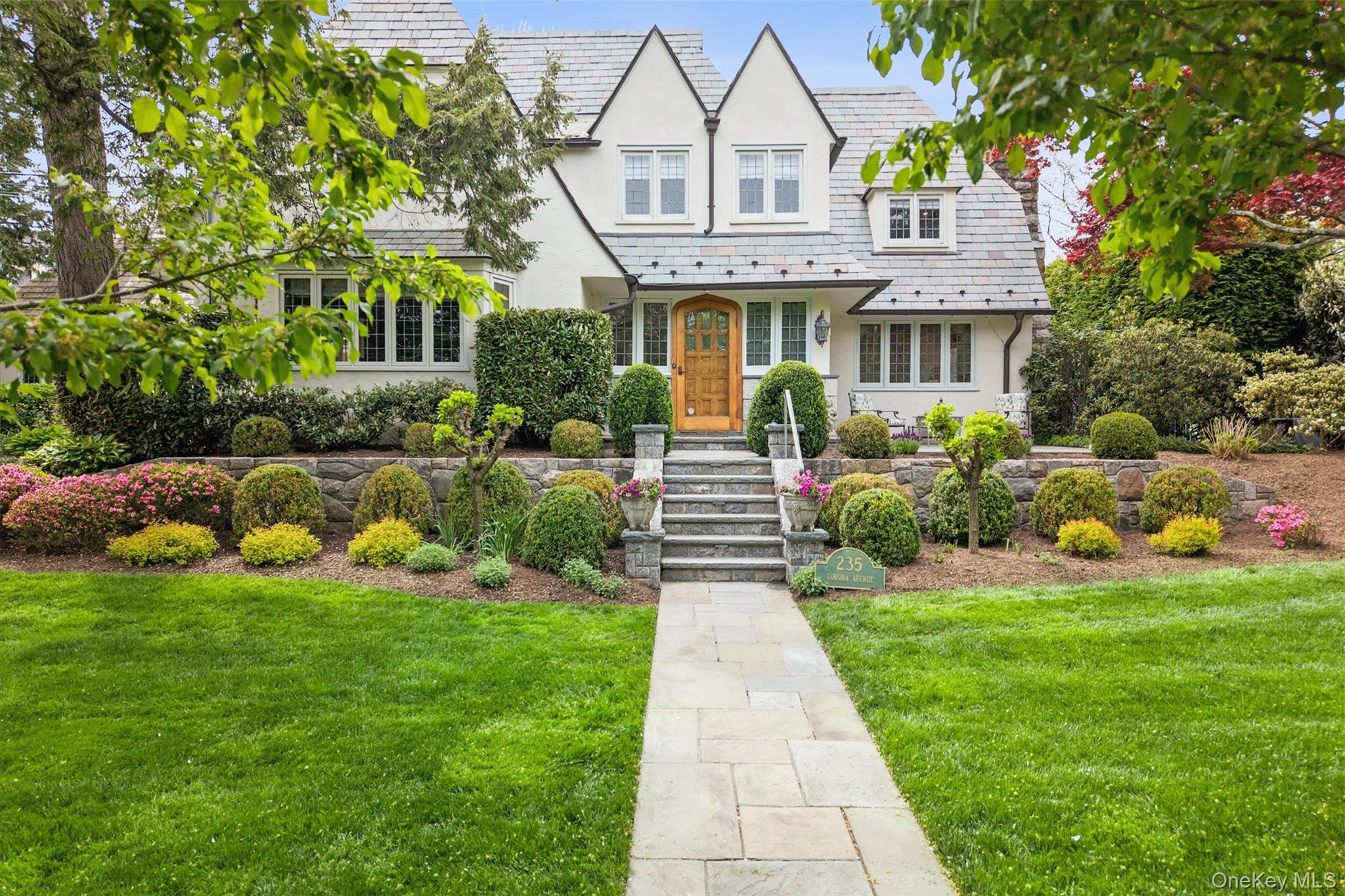 This charming Cotswold Tudor, built in 1919 and located in Pelham Heights, is a rareblend of timeless character and meticulous modern updates. Wrapped in classic stuccowith a slate roof, the home immediately impresses with its leaded glass windows—manynewly installed—and its unmistakable architectural charm.Inside, the residence has been pristinely renovated and thoughtfully maintained, withattention to detail, evident throughout both the interior and exterior. Afoyer welcomes you and provides direct access to a custom-paneledlibrary featuring a ventless fireplace. The living room showcases a cofferedceiling, a wood-burning fireplace, and French doors that open to the patio, creating aseamless indoor-outdoor flow. Adjacent, the gracious dining room offers an ideal settingfor entertaining.The spacious, light-filled kitchen overlooks the beautifully landscaped private gardenand fountain, with direct access to the patio for effortless al fresco dining. A convenientmudroom and pantry sit just off the kitchen.Upstairs, the second floor features four bedrooms, including a primary suite with a largeensuite bath, along with three additional bedrooms and a beautifully appointed hallbathroom. The third floor offers two more bedrooms and a full bath, perfect for guests. The finished lower level (960 additional sq ft) adds even more versatility, featuring a bright office, recreation room, wine cellar, and a half bath.Outside, the garden is a private oasis, entered through wrought iron gatesand highlighted by lush landscaping, a charming fountain, a patio for outdoor dining,and a hot tub for relaxation.Ideally situated close to Metro North, schools, and local shops. This exceptional home offers both convenience and enduring elegance.