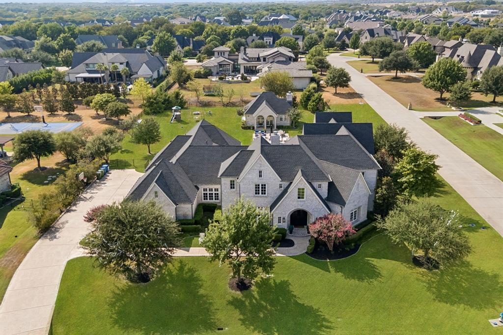 Set on a beautifully landscaped 1.07-acre corner lot in Tranquility Farms, an intimate enclave of approximately 46 estate home sites in highly regarded Lovejoy ISD, this custom Ron McHam estate blends sophisticated interiors with resort-style outdoor living. Seven total bedrooms, seven full baths, one half bath, a separate guest house, and an oversized four-car garage offer exceptional space and versatility.Arched double doors open to rich hardwood floors, refined architectural details, and a gracious living room with a coffered ceiling and statement fireplace. The gourmet kitchen features a generous island with integrated dining, gas range, built-in refrigerator, and separate prep kitchen. A formal dining room and wet bar make entertaining effortless. The secluded downstairs primary suite features a spa-inspired bath with dual marble vanities, freestanding tub, oversized shower, and custom closets with private laundry. Each secondary bedroom includes an ensuite bath. A private downstairs study with pocket doors provides a quiet retreat for work or meetings, while a media and game room, upstairs loft, and additional laundry room enhance everyday living.A sparkling pool and spa, expansive grounds, and covered outdoor living areas with electric retractable screens create an inviting setting for relaxing and entertaining. The separate 999 SF guest house features its own kitchen, living area, bedroom, bath, and laundry, offering flexibility for extended stays or multigenerational living. The oversized four-car garage provides ample room for vehicles and storage.Enjoy convenient access to US 75 and the Sam Rayburn Tollway (SH 121), plus nearby shopping, dining, and entertainment at Fairview Town Center and The Village at Allen. Historic Downtown McKinney’s boutiques, local restaurants, and charming town square are within an easy drive.