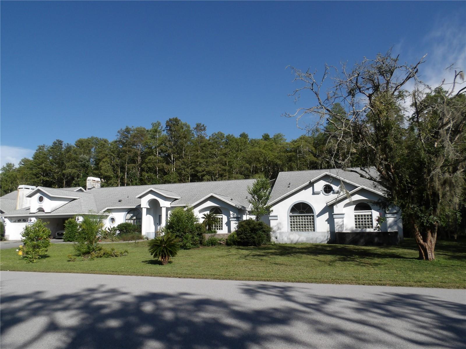 Short Sale. RARE OPPORTUNITY! Restore this exceptional PALATIAL home making it your own showcase masterpiece! This stunning 6 bed/5 bath estate offers TWO ADJOINING HOMES on a full ONE ACRE CONSERVATION LOT in prestigious GATED GRACEWOOD AT RIVER RIDGE community, perfect for multi-generational family living, mother-in-law suite, or rental income opportunity.
EXTERIOR FEATURES:
The exterior welcomes you with elegant stucco architecture and mature landscaping on this private acre lot. The screened lanai showcases a sparkling free-form heated pool and spa perfect for Florida entertaining. Poold deck is in need of repairs.  The spacious 3-car garage provides ample storage and convenience. Included in the sale is a Power Stroke Generator (2.5 yrs old, used 1x, 6000 running watts)  This conservation lot offers ultimate privacy with no rear neighbors and natural beauty of Cypress trees.
INTERIOR FLOW - MAIN HOME:
Step inside to discover an architectural masterpiece with soaring vaulted ceilings and luxurious finishes throughout 5,670 square feet. The gourmet kitchen boasts rich wood cabinetry, granite countertops, and flows seamlessly into the family room. The show-stopping master suite retreat features double door entry with spectacular Grecian columns, rounded walls, fireplace, triple sliders to the lanai, and its own designated electrical panel. The en-suite master bathroom is truly extraordinary with separate vanities, granite countertops, 2-person black jacuzzi jetted spa, bidet, and a walk-through shower complete with 6 nozzles plus waterfall feature. Adjacent to the master suite is a private office with its own bathroom. The enormous bonus room serves perfectly as game room, library, or additional bedroom. Formal living and dining areas along with 2 additional bedrooms, separate office, and 2 fireplaces completing this magnificent main residence.
ADJOINING HOME:
The separate adjoining home features its own private courtyard entry with 3 bedrooms, 2 baths, full kitchen, family room with fireplace, and separate utilities - ideal for guests or rental income.
RECENT UPDATES & LOCATION:
Recent updates include NEW ROOF 2021 and NEW WATER HEATER in main home 2023. Flood insurance is assumable at under $1,000 annually. Located in desirable Gracewood at River Ridge with easy access to beaches, shopping, dining, and medical facilities. Additional features include 3 A/C systems and whole house vacuum system. Just 15 minutes to Gulf beaches and 30 minutes to Tampa International Airport.