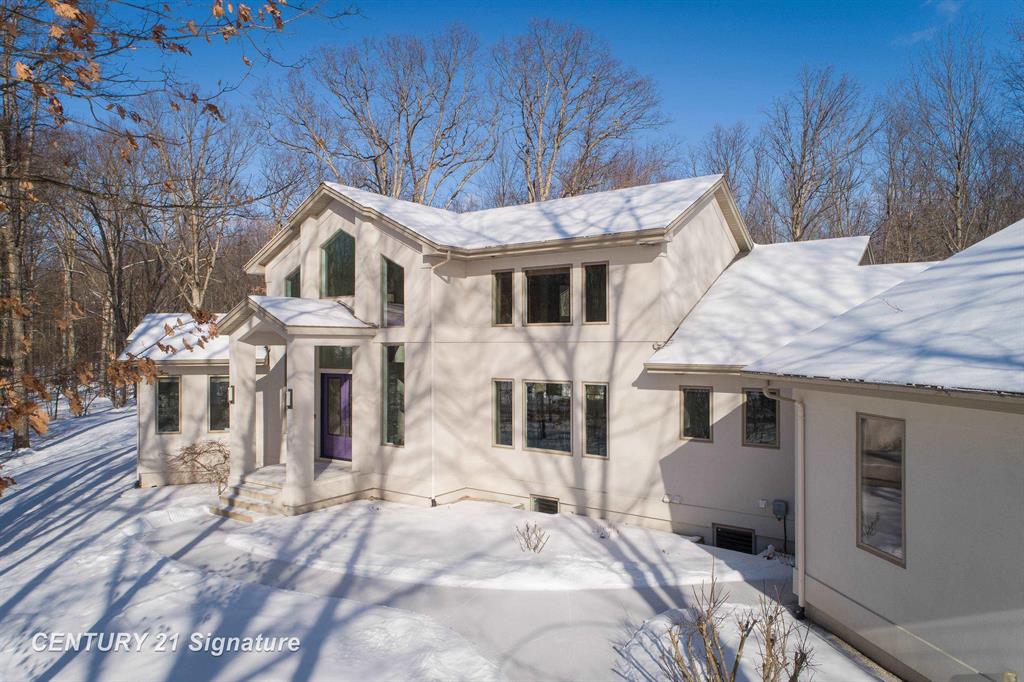 A true architectural statement, this Bill Phillips"“designed estate stands among the most exceptional homes currently on the market. Set on 5.54 private, wooded acres, the residence offers four bedrooms and 4.5 baths, blending refined elegance with thoughtful, high-end functionality throughout. The custom main-floor primary suite is a private retreat, exuding understated luxury. Highlights include a personal fireplace, private deck, and a spa-inspired bath complete with its own fireplace, soaking tub, expansive shower, and exceptional closet space- with bespoke shoe storage. Every detail has been curated to support a sophisticated, yet livable lifestyle. Designed with both entertaining and everyday comfort in mind, the main living areas overlook the serene acreage beyond. Extra-thick Canadian maple flooring flows throughout the home, providing a warm, timeless foundation that beautifully supports transitional d©cor. A striking three-way gas or wood-burning fireplace anchors the space, while floor-to-ceiling windows flood the interior with natural light. The gourmet kitchen is nothing short of stunning, featuring Dacor professional-grade appliances, expansive granite countertops and backsplash, a designer hood vent, generous pantry space, and a custom cookbook cabinet. Dining options are equally impressive, offering seamless transitions from the statement island to a quiet eat-in area, and on to the formal dining room. A butler's pantry with upscale wine refrigeration, abundant storage, and refined lighting provides a second serving area ideal for entertaining. The finished lower level extends the home's versatility, offering a fourth bedroom with private access to a full bath, a dedicated fitness room, workshop, walk-out access to the back patio, and tremendous storage. From construction quality to the strategic sourcing of materials, this home reflects a level of professional design and craftsmanship that is both evident and enduring. The oversized three-car garage easily accommodates more than vehicles, while p