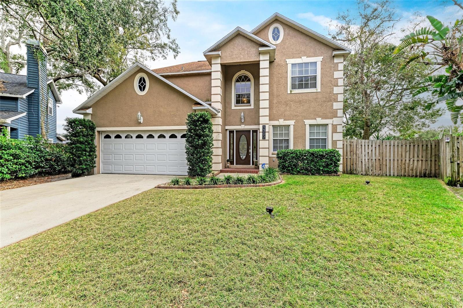 Step into a light-filled sanctuary where soaring 20-foot ceilings, cathedral windows, and architectural elegance define every space. Nestled on a large cul-de-sac lot in a custom-built community of just 15 homes, this beautifully upgraded property blends privacy, style, and comfort with abundant space for entertaining and relaxing—indoors and out. The heart of the home is a dramatic great room with double-height ceilings, a striking wood-burning fireplace clad in marble tile with a carved wood mantle, and expansive windows that bathe the space in natural light. A charming catwalk with wood spindles and an oak banister overlooks the great room from upstairs, creating an open and airy flow throughout the upper level. Upstairs, the primary suite is a true retreat, featuring a large walk-in closet with custom built-ins, a spa-inspired bathroom with a whirlpool soaking tub, dual vessel sinks, and an expansive walk-in shower with dual showerheads. Just down the catwalk, the third bedroom doubles as a second primary suite, complete with its own en suite bath and generous walk-in closet—perfect for multi-generational living or guests. All bathrooms have been thoughtfully updated, combining modern finishes with timeless design. The remodeled kitchen (2020) is both stylish and functional, featuring sleek stone countertops, modern white cabinetry, black stainless-steel appliances, a reverse osmosis system, a closet pantry as well as a huge walk-in pantry cleverly tucked beneath the staircase. The open layout connects seamlessly to the rest of the home, including a separate dining room, currently used as a second home office. The downstairs bedroom is privately tucked away and is also currently being used as a home office. Throughout the home, enjoy luxury vinyl plank flooring—no carpet in sight—for a clean, low-maintenance lifestyle. Additional features include built-in pest control tube system and subterranean termite bond with a transferable warranty, a shed for extra storage, and a new roof installed in 2020 and a new AC unit installed 2024. Step outside your double French doors to your own fully fenced private oasis: a massive 128-foot composite wood deck, concrete paver walkways, and a spacious grassy side yard – all shaded by mature tropical trees and oaks. Whether you’re hosting a gathering or unwinding under the canopy of green, the backyard offers versatile outdoor living like no other. This one-of-a-kind property offers custom design, smart upgrades, and a truly rare setting—a home that checks every box. Don’t miss your chance to own in one of the area’s most desirable hidden-gem communities.