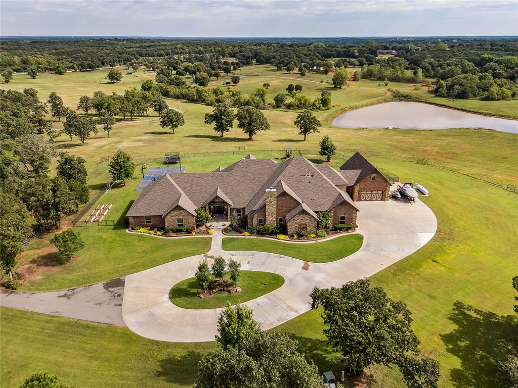 Experience refined luxury and self-sufficient living on this 142.3-acre private estate—crafted with exceptional detail and design. The primary suite impresses with a vaulted beam ceiling, hand-scraped walnut floors, and a wood-burning fireplace with a cozy sitting area. Its spa-style en-suite features a walk-in shower with dual heads, a large soaking tub, and an oversized walk-in closet that doubles as an F5-rated safe room. Each secondary bedroom includes its own private bath and walk-in closet. The executive office offers hand-scraped wood floors and built-in shelving, while the gourmet kitchen is a chef’s dream—complete with two islands, farmhouse and prep sinks, two dishwashers, reverse osmosis water filtration system, South-Bend 10-burner gas stove with double ovens and broiler, custom vent hood, Sub-Zero refrigerator/freezer, and walk-in pantry with custom wood accent above the kitchen. The laundry room includes dual washers and dryers, a rolling island, wash sink, built-in storage, mudroom, and secondary office space. Upstairs features a game room, media room, and exercise room, while a climate-controlled dog room with auto door and wash area enhances everyday convenience. Luxury continues with vaulted beam entry and formal living room, motorized shades, plantation shutters, smart thermostat, spray foam insulation, private sauna and security system with 8-zone cameras. Outdoors, enjoy a 35,000-gallon heated saltwater pool with tanning ledge, diving board, slide, and 10-person hot tub. A 20x40 sports court features three basketball goals, pickleball/volleyball lines, and LED lighting. The 8-stall horse barn includes a tack room, wash rack, and roll-up doors, surrounded by six pastures and three paddocks with water access. Property also includes four water wells, large pond, Rain Bird sprinkler system, and two rental homes—perfect for guests or income opportunities. Every detail of this estate blends comfort, elegance, and functionality in perfect harmony.