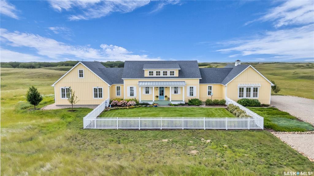 Situated on six acres just 10 minutes south of Saskatoon, this custom-built home by luxury builder Maison Design blends elegance, comfort, and functionality.  The property welcomes you with a charming white picket-fenced yard.  Inside, a spacious foyer opens to a bright, open concept living area with vaulted beadboard ceilings, a gas fireplace with a unique rustic wood surround, flanked by dual French doors.  Engineered hardwood floors run throughout the home, with tiled floors in select rooms.  The roomy powder room is smartly located just off the foyer.  The dining room and kitchen area have high bead board ceilings, and standout light fixtures, with plenty of space for entertaining.  The kitchen is a true showpiece and features two pantries, including a butler’s pantry.  Premium appliances include Miele, Thermador and Sharp, and there are 2 kitchen sinks.  The freezer and a wine cooler are conveniently located in the butler’s pantry.  Kitchen brick wall tile is a standout feature.  This very kitchen has been featured on the AyA Kitchens website. The large laundry/mudroom features custom cabinetry and tile floors, leading to a three-bay heated garage. There are three bedrooms, including a primary suite with a large walk-in closet, an oversized en suite with heated floors, a whirlpool tub, tiled shower, and two private toilets.  The second and third bedrooms share a bathroom.  The property is beautifully landscaped with stamped concrete walkways, river rock borders, 19 mature trees, and many shrubs/perennials. An automated sprinkler/irrigation system is supported by a 55-foot well. The fenced-in backyard includes pergola and lattice structures. The outdoor space is as functional as it is stunning. Additional features include 2-zone heating/cooling, a tankless water heater, RO water filtration, and satellite Wi-Fi. Close to Beaver Creek Conservation Area, Dakota Dunes Casino/Golf Course, this acreage offers the best of both country living and city convenience.
