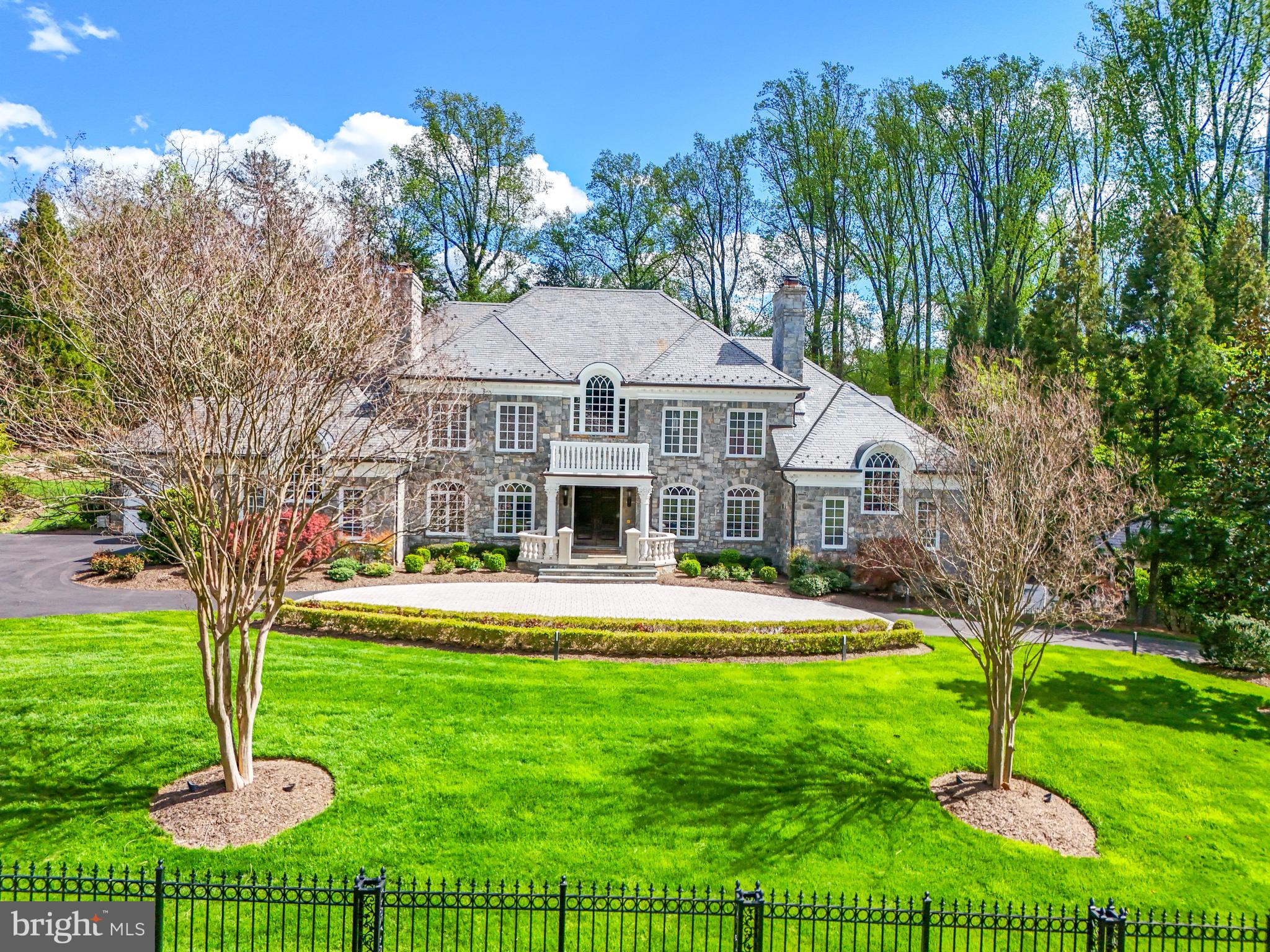 Welcome to 1221 Mottrom Drive. A Private Oasis in a Coveted Location. This spectacular estate, well over 12,000 square feet, is nestled in one of the area's most sought-after neighborhoods and crafted by renowned builder George Sagatov. Privately gated and set behind a circular driveway, the home makes an unforgettable first impression with its striking curb appeal, lush professional landscaping, and a sparkling resort-style pool. Step inside the grand two-story foyer, where a dramatic curved staircase sets the tone for the refined interiors that follow. The formal living room and banquet-sized dining room each feature their own fireplaces, elegant mantels, and arched doorways that add architectural charm. The heart of the home is the breathtaking great room with a floor-to-ceiling stone fireplace, coffered ceiling, and a wall of windows that flood the space with natural light and offer seamless access to the custom deck, perfect for indoor-outdoor living. The chef’s kitchen features custom cabinetry, a large center island, two dishwashers, a built-in coffee maker, warming drawer, and a work desk area. Also on the main level is a richly paneled private office with built-ins and a fireplace, as well as a spacious main-level primary suite with a walk-in closet and luxurious bath complete with separate vanities. Two powder rooms and a well-appointed laundry room complete the main floor.Upstairs, the impressive owner’s suite is a true retreat with its own sitting room, fireplace, two generous walk-in closets, and a spa-like bathroom with separate vanities, soaking tub, and oversized shower. Three additional ensuite bedrooms provide comfort and privacy for family and guests. The walk-out lower level is an entertainer’s dream, featuring a fully equipped wet bar, wine cellar, state-of-the-art media room with tiered seating, a fitness room with sauna, a recreation room with stone fireplace, and an additional bedroom and full bath. Step outside to a true backyard paradise. The sparkling pool is complemented by a fully outfitted pool house with a full kitchen and bath, perfect for summer entertaining. Every detail of this home has been thoughtfully curated for luxurious living, all just minutes from the shops, restaurants, and commuter routes of Tysons Corner.