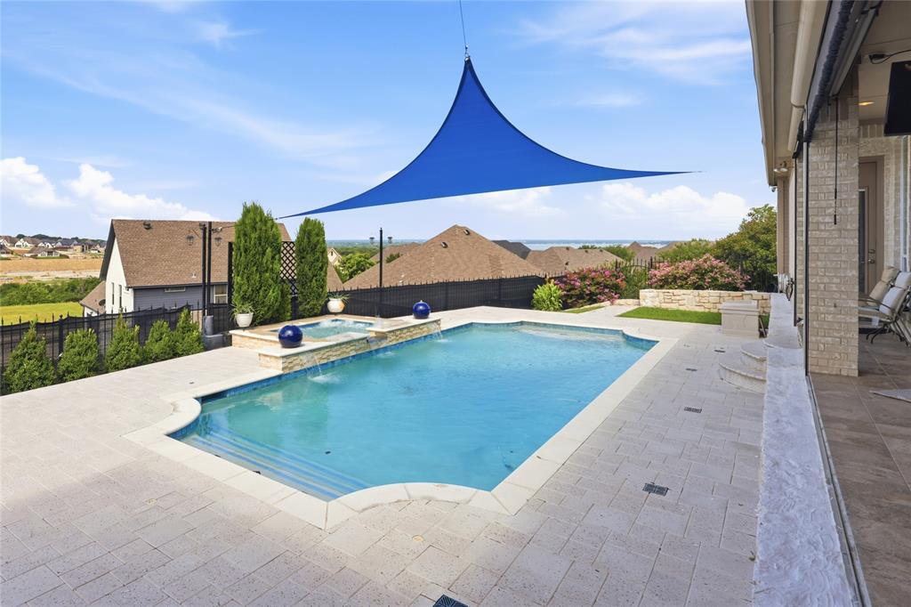 Experience luxury living at this exceptional 3 bed, 3 bath, 3,099 sq. ft. estate in North Fort Worth near Eagle Mountain Lake. This property combines masterful interior design with an entertainer's outdoor paradise. Step through the entryway featuring custom Chicago-imported stained glass into an open concept living area with soaring 12+ foot ceilings with elegant crown molding, where newly refinished hardwood flooring guides you through the open spaces. The layout features a dedicated study that could easily serve as a fourth bedroom, secondary rooms with unique features like a built-in wet bar, and multiple hidden safes for secure storage. In the chef’s sanctuary, an open kitchen boasts premium granite countertops, beveled-glass custom cabinetry, a massive power-equipped island, a pot filler, and a skylight. The primary retreat allows you to unwind by your private gas fireplace or step into the fully remodeled primary bathroom featuring double vanities, an expansive walk-in closet, a soaking tub, and a steam shower. Outside, you can take in breathtaking views of Eagle Mountain Lake from your custom saltwater pool, which was completely reimagined in 2020 and comes complete with cool-deck tiling, a heated hot tub, and a dedicated sun-shade canopy. The spacious covered back porch features an outdoor kitchen with a gas grill, external venting, remote-controlled sun shades, and a fold-down TV setup, creating the perfect space for hosting. Additional exceptional extras include two distinct side yards, an electronic wrought iron driveway gate, a newly repoured driveway, and a pristine, epoxied 3-car garage. Furthermore, massive attic spaces include a 200 lb lift system and ample room for a future second-story conversion, making this home as functional as it is beautiful. Interior of the home painted October 2026. Come take a look at this GORGEOUS property1