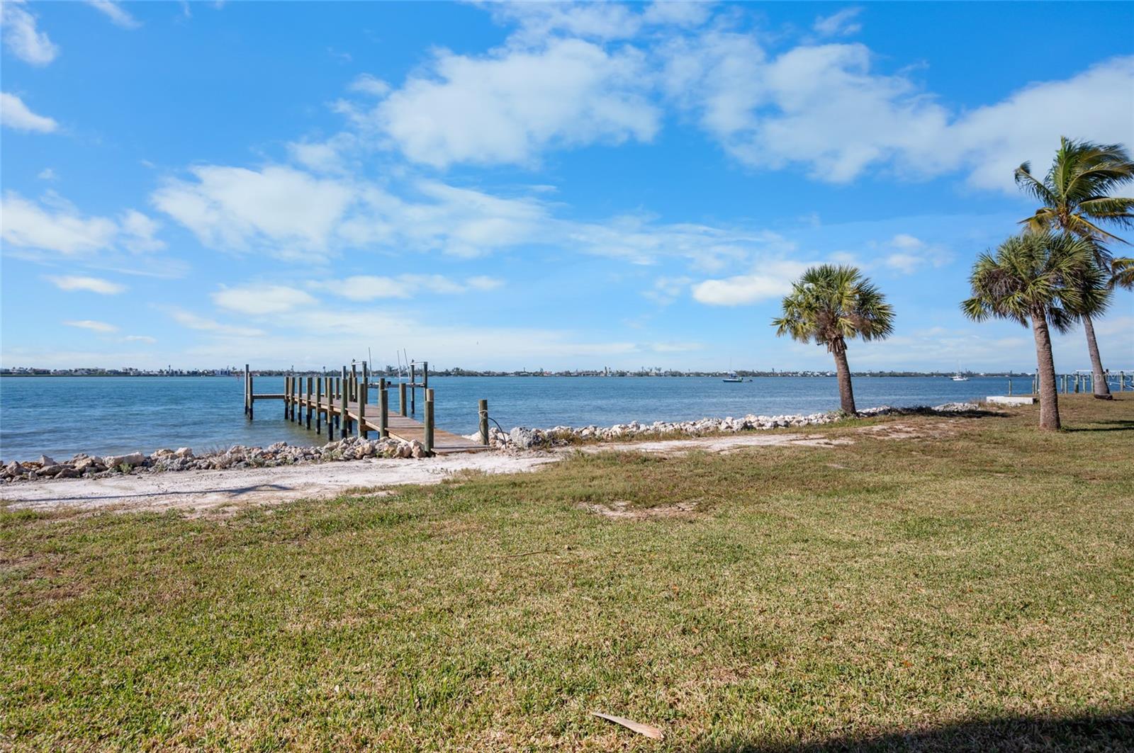 One or more photo(s) has been virtually staged. Wake up to sweeping, unobstructed views of Lemon Bay and step directly into true waterfront living. This fully remodeled coastal retreat is centered around DIRECT BAY FRONTAGE, a PRIVATE DOCK, and a 10,000 LB BOAT LIFT, with NO FIXED BRIDGES between you and the open Gulf. From your backyard, enjoy immediate boating access, endless sunsets, and front-row seats to dolphins and manatees passing by. ~~~Inside, the open, light-filled floor plan is designed to keep the water as the focal point. TRAVERTINE flooring flows through the main living areas, while the expansive great room opens wide through pocketing sliding doors that frame the bay. The kitchen connects seamlessly, featuring GRANITE COUNTERTOPS, waterproof-faced solid wood cabinetry, stainless steel appliances, and a LARGE ISLAND WITH BREAKFAST BAR SEATING, all positioned to enjoy the view. ***Outdoor living is where this home truly shines. The SCREENED LANAI WITH PANORAMIC SCREENS captures uninterrupted water views and glowing sunsets. The open patio with RETRACTABLE SUNSHADE invites year-round relaxation, while the oversized waterfront lot with thoughtful shading provides welcome relief from the Florida sun, allowing you to enjoy the yard and waterfront comfortably even during warmer months. ~~~HURRICANE IMPACT WINDOWS THROUGHOUT the home provide peace of mind. The split floor plan offers privacy and comfort. Two remodeled guest bedrooms share a modern bath, while the primary suite serves as a private waterfront retreat with lanai access, a wall-length closet with built-ins, and a SPA-INSPIRED EN SUITE BATH with refined finishes. ***The PRIVATE DOCK is the heart of the lifestyle here. Fish from your backyard, cruise straight to the Gulf with Stump Pass being about a ten-minute boat ride away, or explore up to four nearby beaches on Manasota Key. ~~~With no rental restrictions, this property also offers strong income and long-term investment potential. An ADJACENT PROPERTY IS ALSO AVAILABLE FOR PURCHASE in a separate listing, and when combined, the two parcels offer OVER AN ACRE OF PRIME WATERFRONT LAND, presenting a rare opportunity for expanded use or future development. ***Just two miles from Englewood Beach and 1.5 miles from historic Dearborn Street, this property delivers unmatched access to dining, shopping, entertainment, and some of the best boating on the coast. A rare Lemon Bay offering where dock, water views, and Gulf access take center stage.