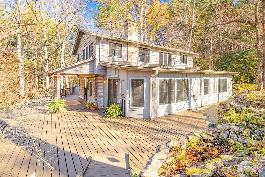 A true paradise for horse and nature lovers! This serene 8.17-acre property offers privacy, peace, and endless possibilities. Perfect for horses, livestock, farming, gardening, a flower farm—or simply a private retreat. The cozy living room, originally an 1800s chestnut oak cabin, features a woodstove and combines rustic charm with modern comfort. It opens into a spacious eat-in kitchen, ideal for gatherings. A bright and inviting sunroom overlooks wildflower gardens and a soothing waterfall. Upstairs, you’ll find a full bath, a primary bedroom, and three additional bedrooms. Unique architectural touches include recycled Douglas fir beams. Radiant floor heat in the downstairs bathroom and laundry room. Enjoy outdoor living on the expansive front porch and wrap-around deck, or relax in the fully fenced yard—perfect for pets. A registered Monarch Waystation and part of the Butterfly Highway, this home is a haven for pollinators and nature watchers alike. Just 20 minutes from Asheville and close to local breweries, hiking trails, and more.