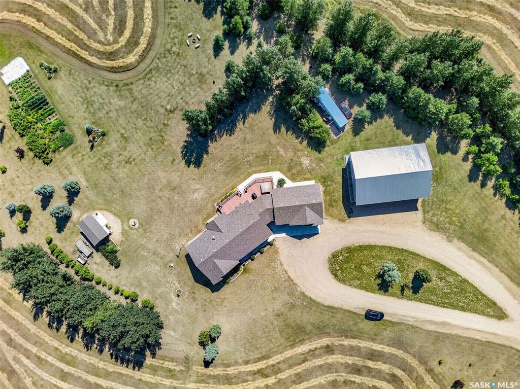 Welcome to this exceptional custom-built acreage situated on 39 picturesque acres with the convenience of all pavement to the driveway. Thoughtfully designed and built by the original owner, this impressive home showcases quality craftsmanship, spacious living, and breathtaking prairie views.  Step inside to a welcoming foyer that opens into a stunning great room with soaring vaulted ceilings and an abundance of natural light. The open-concept layout seamlessly connects the living, dining, and kitchen areas, creating the perfect space for everyday living and entertaining. The chef-inspired kitchen features quartz countertops, a large island, stainless steel appliances, and a natural gas hookup for a future gas range. The living room fireplace and dryer are also connected to natural gas for added efficiency. From the kitchen, step onto the expansive low-maintenance composite deck and enjoy peaceful Saskatchewan sunsets overlooking your private acreage. The main floor offers three generously sized bedrooms, a dedicated home office, and a spacious four-piece bathroom. The primary suite provides a relaxing retreat with a walk-in closet and private three-piece ensuite. The fully developed basement offers exceptional flexibility with a massive recreation area ideal for a games room, home theatre, fitness space, or entertaining all with in floor heat. A convenient wet bar with sink and fridge adds to the functionality. Two additional large bedrooms, a four-piece bathroom, and ample utility and storage space complete the lower level plus an impressive ICF basement. Heated floors in bsmt.  The attached heated garage features in-floor heat, while the impressive shop is equipped with two welder plugs, and RV hookups, making it ideal for hobbyists, tradespeople, or equipment storage. Designed for year-round comfort, the home is serviced by a private well with a computerized pressure system, water softener, and an efficient boiler hot water heating system. Pavement to property.
