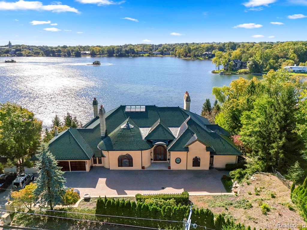 Discover unparalleled luxury on the shores of Island Lake in this 14,000+ sq ft estate, designed for elegance, comfort, and sophistication. South-facing and filled with natural light, this residence features 4 spacious bedroom suites—including a his-and-her primary with a spa-like bath and expansive walk-in closet—and 5.3 baths throughout. The gourmet kitchen is equipped with top-tier appliances including a Sub-Zero fridge, Viking stove, SieMatic cabinetry, and radiant-heated travertine floors. Entertain in style with a formal dining room, a living room offering panoramic lake views, and a mahogany library with coffered ceilings and built-in bookshelves. A secret passage connects the living room to the office for added charm. The fully finished lower level includes a second kitchen, an imported Italian bar, wine cellar, gun room, daylight bedrooms (one with walk-out), and lake views throughout. Step out to the balcony or terrace with a retractable awning and enjoy the professionally designed drainage system and lower-level garage for lakeside storage. Additional highlights include an elevator to all three levels, radiant heating powered by two boilers (one new in 2024), electronic shades, new windows, copper gutters, clay tile roof, and a backup generator. Furniture is negotiable. Some rooms remain unphotographed for privacy. A true lakeside masterpiece blending timeless elegance with modern luxury.All measurements are approximate agent to verify.
