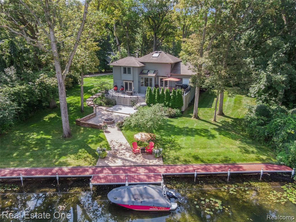 Waterfront paradise on one of the most prestigious enclaves along the Huron River Chain of Lakes and Lakeland Trail! This custom built home offers a life where craftsmanship, comfort, and waterfront beauty come together. Nestled on a sprawling 1.3 acres of professionally landscaped grounds, including sprinkler system and solar lighting for appeal through the seasons, this home commands 350 feet of private canal frontage leading directly to Zukey Lake, complete with a seawall to protect and define your shoreline. Inside, a two story foyer opens to living and dining rooms with soaring ceilings and floor to ceiling windows that bathe the space in natural light. Thoughtful upgrades set the tone including a newly updated kitchen with premium finishes like huge center island with granite countertops, plentiful shaker-style cabinets with modern pulls, stainless appliances, and large pantry. Updated guest bedroom and bath and laundry room.  Enjoy a sun soaked breakfast from the nook with skylights while overlooking the canal views out back. This home's custom design features an open, sunken living space just off the kitchen—allowing you to stay connected to the conversation and energy of guests below while enjoying the ease and functionality of meal prep above. Upstairs, the primary suite elevates daily life with walk in closet and a spa-inspired bath, shower, and separate walk in closet. The partially finished lower level offers an added 1,400 square feet with soaring 10-foot ceilings, a recreation room, and hobby space, extending the home’s versatility. Outdoors, over 2,000 sqft of multi-level patio and deck provide the ultimate setting for summer gatherings after a day of boating, paddling, or cruising the river. Whether you’re drawn to the tranquility of private wooded acreage, the thrill of waterfront living, or the refinement of a home built to last, this is more than a residence—it’s a destination. Schedule your showing today!
