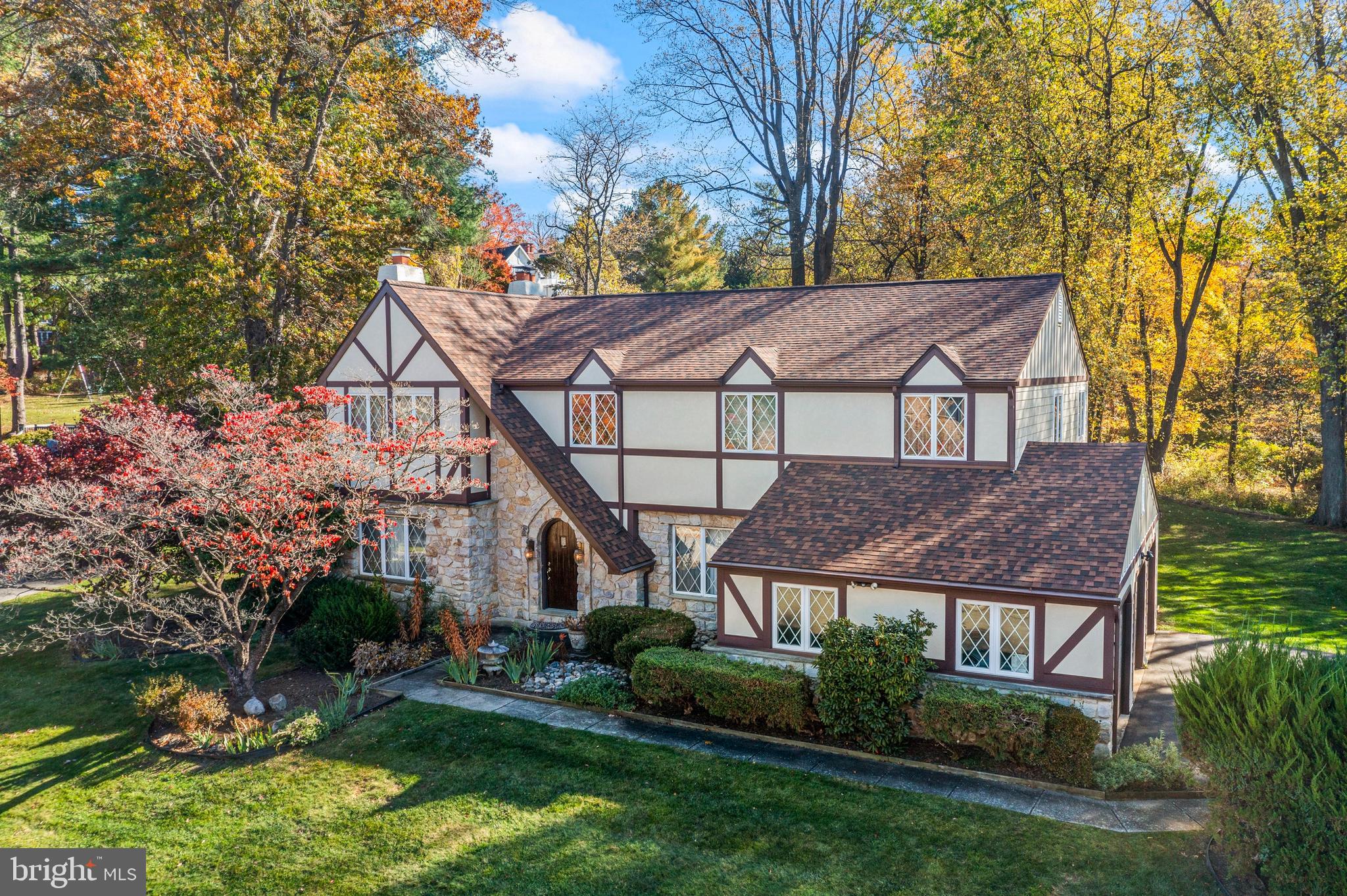 Welcome to 806 Northwinds Drive in the sought-after Radnor Chase neighborhood of Bryn Mawr—an exceptional Tudor-style residence offering over 4,000 square feet of beautifully designed living space in a premier Main Line location. Nestled within the highly ranked Radnor Township School District, this home combines timeless architecture, generous proportions, and a setting that’s simply hard to match.A soaring two-story Entrance Hall creates a dramatic first impression and is flanked by a gracious Living Room with fireplace and an elegant Dining Room highlighted by large windows and abundant natural light. The rear of the home features today’s highly desirable open-concept layout, offering seamless flow and sightlines between the Kitchen, Breakfast Area, and Family Room—perfect for both everyday living and entertaining.The Kitchen is appointed with warm wood cabinetry and granite countertops, opening directly to the inviting Family Room with its floor-to-ceiling stone fireplace. Just beyond, a spectacular Sunroom addition with vaulted ceiling and walls of windows provides panoramic views of the scenic rear yard and fills the home with natural light year-round.The first floor also includes a stunning vaulted Office addition with built-ins on three walls, ideal for working from home; a spacious Mudroom/Laundry Room; a Powder Room; and convenient interior access to the three-car Garage.Upstairs, the expansive Primary Suite offers a private retreat, complete with a Sitting Area (ideal for a second office or reading nook), a large walk-in closet, dressing table area, and a luxurious Primary Bath with deep soaking tub and separate steam shower. Three additional generously sized Bedrooms share an oversized Hall Bath.The finished Lower Level provides remarkable flexibility, with multiple areas for TV and media, a game table, exercise space, and a separate room suitable for guests or an au pair. Abundant built-in shelving in the unfinished basement area and garage ensures exceptional storage throughout.Outdoor living is equally impressive. Relax on the composite rear deck overlooking the picturesque yard, which adjoins neighborhood open space to the rear and right—offering privacy and a beautiful natural backdrop.Recent improvements, including newer roof, windows, deck, exterior cladding, hot water heater, and HVAC systems, provide tremendous peace of mind.Enjoy easy access to the shops and restaurants of Wayne and Bryn Mawr, nearby universities, train stations, medical and corporate centers, Center City, and Philadelphia International Airport. This is a rare opportunity to own a spacious, beautifully maintained home in one of the Main Line’s most desirable neighborhoods.