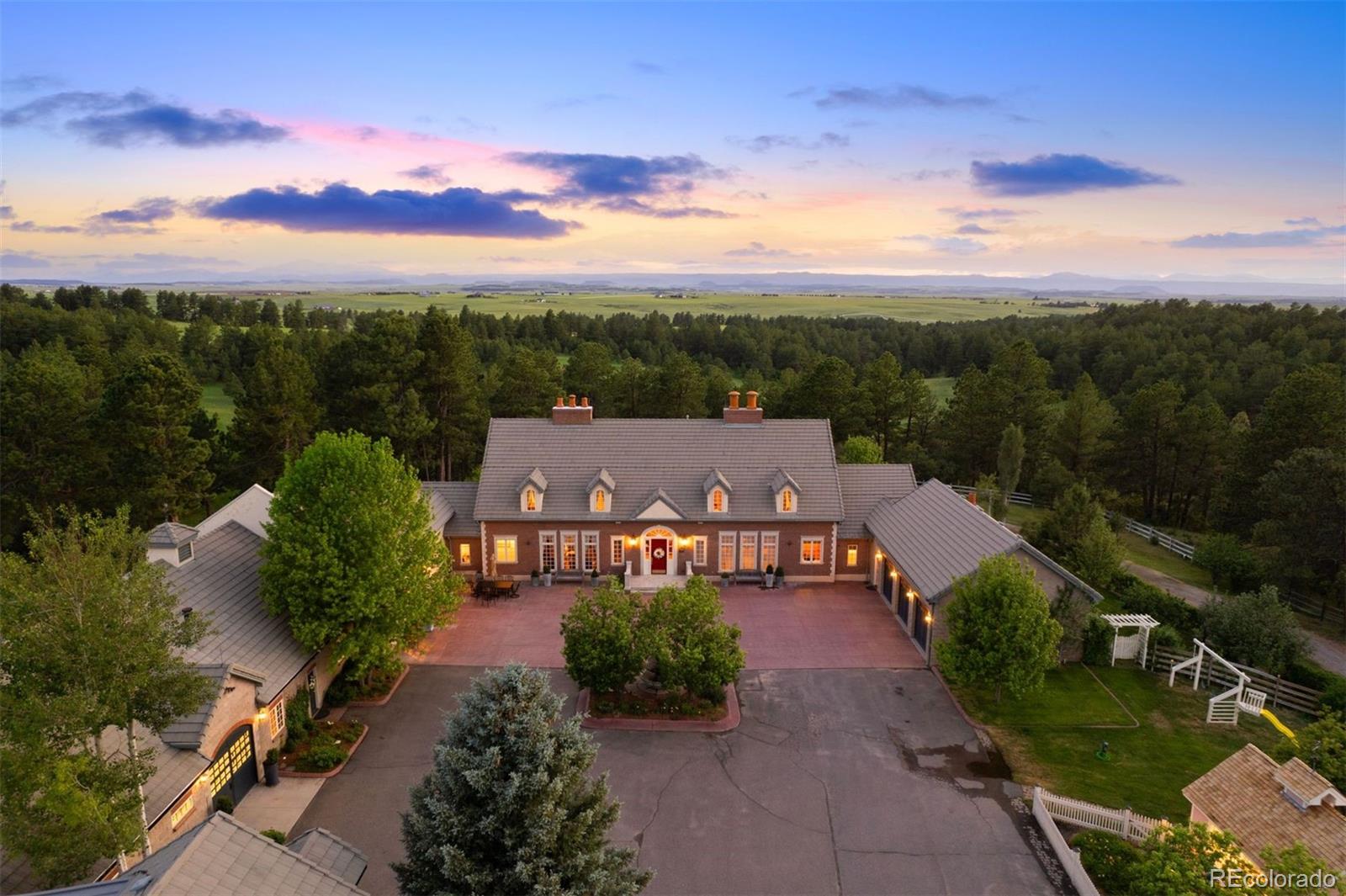 80 acres of ponderosa pines, native grasses, and seasonal wildflowers - Thistle Hill Farm is a home designed equally for equestrians and those drawn to the quiet beauty of country living. A gated drive arrives at a circular courtyard and the stately residence with stables, a flex room, separate apartment, and garages on two sides.  The entry hall is an architectural statement, passing through the home from east to west. It opens into the dining room and great room, where 20-foot ceilings and a full wall of windows bathe oak floors in daylight. The dining room seats 14 to 16 guests while retaining an intimate atmosphere. The kitchen features a butcher-block island and a hand-painted tile backsplash that adds warmth and artistry.  The private wing houses a serene primary suite, a study with custom fireplace, and a sunlit exercise room with woodland views. Gallery access connects to the flex room, a distinctive space adaptable as a gym, studio, entertaining hall, or collection display area.  Outside, terraces and patios wrap every side of the home, an open invitation to enjoy the park that surrounds you. The west terrace highlights spectacular sunsets, while the kitchen patio with its fireplace, awning, and herb garden is a lovely spot day or night.  With magnificent terrain and beautifully designed barns, Thistle Hill Farm is a horse property perfect for most disciplines. Indoor access leads to the heated stable with seven stalls, a wash stall, four tie stalls, tack room, hay storage, and a full bath with laundry. A second barn adds 4 stalls, an indoor round pen, and covered hay storage. The existing outdoor arena offers an ideal site for an indoor arena, with another location nearby perfectly suited for an outdoor arena. A two-bedroom apartment offers flexible accommodations for guests or caretakers. Mineral and water rights included.