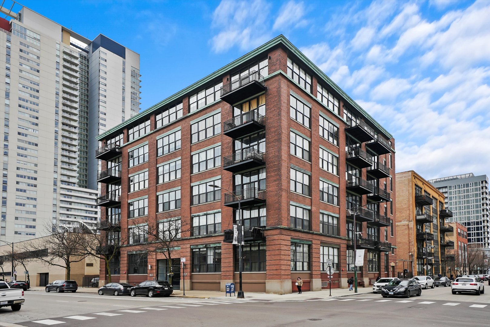 Welcome to Washington Blvd Lofts, where historic character meets modern luxury in the heart of the West Loop. This sun-filled 2-bedroom, 2-bath loft-style condo was fully reimagined in 2023 with custom details at every turn. Soaring 12-foot ceilings, exposed brick, and oversized 8-foot windows create a dramatic, light-filled backdrop, while the kitchen features refinished cabinetry, new hardware, a sleek backsplash, and designer lighting over the island. The open-concept living and dining area is anchored by a striking custom fireplace with integrated uplighting, concealed storage, and a built-in electric drop for seamless TV mounting. The primary suite is a tranquil retreat with a bespoke accent wall, plush carpeting, custom closet build-out, elegant sconce lighting, and a handcrafted sliding door for privacy, while the second bedroom offers equal versatility with a custom wardrobe, and sophisticated millwork. Both bathrooms are beautifully appointed with modern tilework and seamless glass showers. Additional highlights include a dramatic foyer with perimeter accent lighting, statement wallpaper, a custom millwork feature wall flowing into the main living space and USB/USB-C enabled outlets. Step outside to an expansive west-facing balcony with breathtaking sunset views. Converted to condos in 2000, this professionally managed building offers superior construction with 15 inches of concrete between floors. The home includes a spacious storage cage (#507) and a secure deeded outdoor parking space (#21), included in the listing price. Ideally located, this home is steps from Mary Bartelme Park, Mariano's, Whole Foods, Target, and local markets, with easy access to Restaurant Row, Fulton Market, Madison Street, I-90/94, I-290, Metra, and CTA, offering the ultimate West Loop lifestyle.