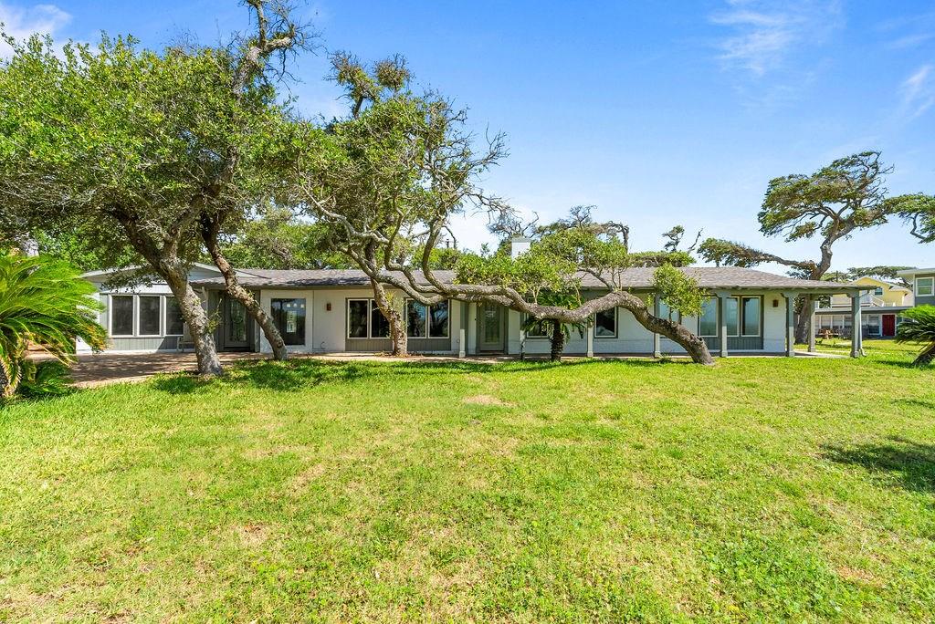 !!NEW PRICE!!---MAIN HOME | GUEST HOUSE | EFFICIENCY AND GARAGE--Live Life Well – Waterfront Elegance on Aransas Bay.  Experience refined coastal living at this exceptional 1-acre waterfront estate, where panoramic Aransas Bay views and timeless elegance define every detail. Tucked beneath the sweeping branches of mature live oaks, this private retreat offers a rare blend of sophistication, serenity, and space. The main residence features four generously sized bedrooms, each designed to showcase the stunning bayfront scenery or famous windswept live oaks. Thoughtfully crafted for comfort and entertaining, the home's layout invites effortless indoor-outdoor living. A beautifully appointed detached guest house with a kitchenette provides elegant accommodations for visiting guests, while a separate caretaker's apartment above the two-car garage ensures seamless estate management or additional guest space. Whether you're enjoying sunrise views from the porch or hosting evening gatherings under the stars, this waterfront sanctuary offers a lifestyle of grace and ease. Luxury, privacy, and tranquility—live life well on Aransas Bay.