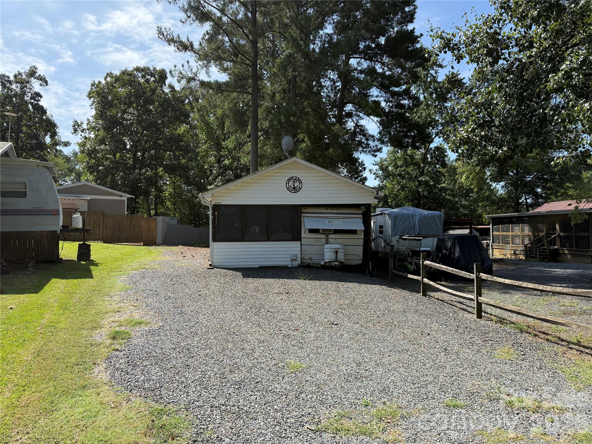 Great opportunity to get started here in the park. This unit is close to the gate for easy access. They have bought a nice size piece of common area that now belongs to this lot. See Photo attached. Plenty of parking for everything you may have. Step into the large family room with dining room booth. Ready for games, meals or just TV. Enter into the camper with sleeping to the right and the primary bedroom in the back. 50 Gal Elec Water heater. Camper Heat and 2 window units for a/c. Storage building out back as well as a small deck for grilling. Most furnishings to remain.  Come and see if this is your "Happy Place" here in the park.All buyers must be with a realtor to gain entry to the park.