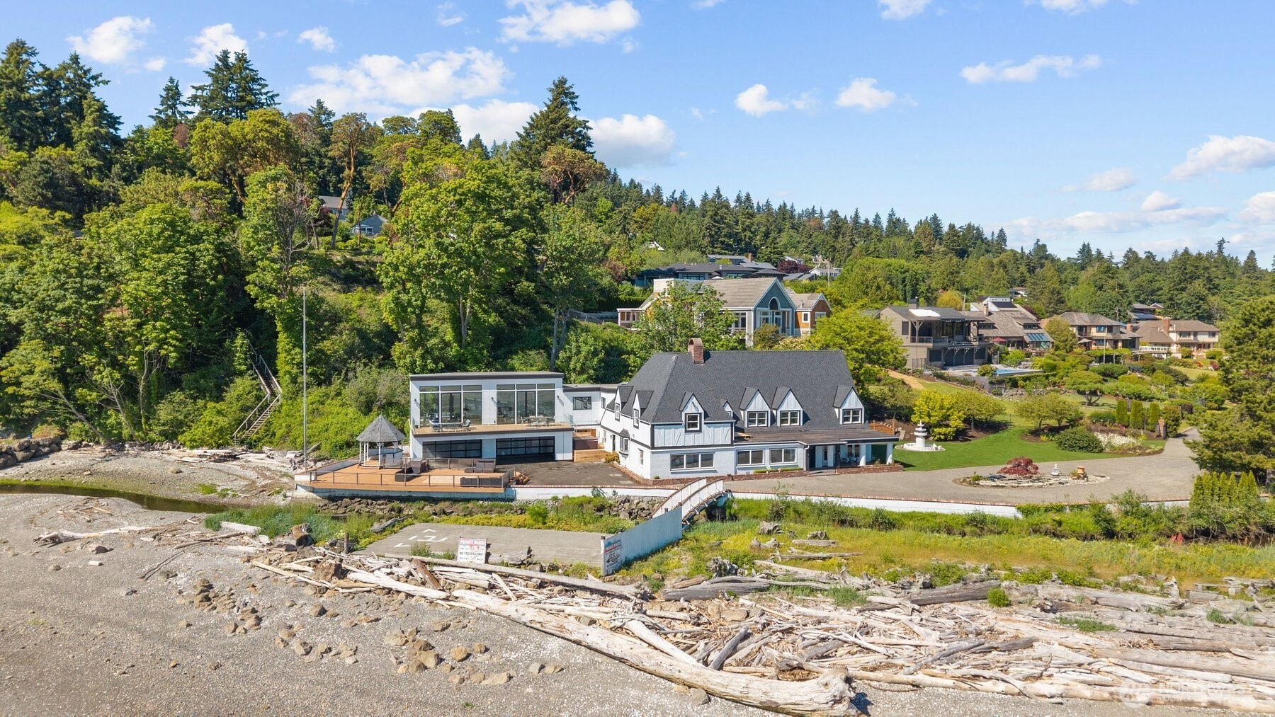 Experience the pinnacle of PNW waterfront living in this fully reimagined Normandy Park estate. Set along the serene shores of Puget Sound, this rare property captures unobstructed 180° views of Vashon & Maury Islands, Point Robinson Lighthouse and the Olympic Mountains. With a private helipad, 100 ft of prime Sound waterfront, Miller Creek frontage, and adjacency to The Cove wildlife sanctuary, this estate offers a level of privacy, setting and lifestyle rarely found.Believed to have once served as the original Seattle-Tacoma Land Company clubhouse associated with Normandy Park’s historic Cove/Lot A waterfront community, the home carries a rare connection to the area’s earliest chapter. Completely remodeled, it blends classic Tudor character with modern luxury, seamlessly blending the original residence to a dramatic upper great room, where walls of windows frame expansive Sound views and fill the home with natural light.Expansive decks invite effortless indoor/outdoor living, while generous gathering spaces, a 4-car garage and a nearby boat port at the Cove support both everyday comfort and large-scale entertaining. Major updates include a new roof, hardwood floors throughout, remodeled kitchen and baths, smooth-coated and freshly painted walls, new trim, exterior paint, updated windows and doors, and more. A true legacy property in one of Normandy Park’s most treasured settings—an exceptional blend of history, privacy, modern design and iconic Pacific Northwest beauty.