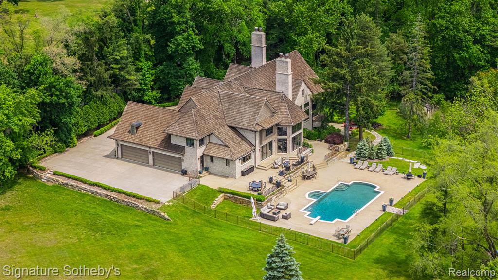 Set on 5.5 manicured acres minutes from downtown Franklin, this estate blends commanding architecture with a warm, modern sensibility. Offering over 6,781 square feet of living space, plus a fully finished lower level, the home features 6 ensuite bedrooms and 7.2 bathrooms—crafted for grand-scale living and effortless entertaining. A soaring double-height foyer sets an elegant tone, flowing into the main living space where rich hardwoods and coffered ceilings anchor the open floor plan. The chef’s kitchen is a study in symmetry and functionality, fitted with Sub-Zero and Wolf appliances, custom cabinetry, and double oversized islands that connect seamlessly to the great room, where floor-to-ceiling windows frame serene views of the grounds. A richly paneled library with built-in shelving, a fireplace, and a dramatic arched window offers a private setting for work, reading, or quiet reflection. The rare first-floor primary suite offers a true sense of retreat. Designed with privacy and comfort in mind, it features dual walk-in closets and two completely separate spa-inspired bathrooms—each appointed with high-end finishes, custom vanities, and generous showers. A private balcony off the suite offers a tranquil vantage point to overlook the estate’s expansive acreage, creating a seamless blend of luxury and nature. Downstairs, the walkout lower level has been transformed into a lifestyle destination: a custom-built theater with 8K projection, a full sports court with new flooring, and an expansive living area with full kitchen. Outdoors, a fully resurfaced gunite pool, new mechanicals, and an extended patio provide the ideal backdrop for seasonal entertaining. Additional highlights include a Control4 smart home system, new full-home generator, five furnaces with corresponding AC units, an attached 4-car garage, and so much more. This is a legacy-caliber offering—sophisticated, bold, and completely turnkey.