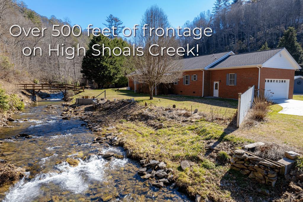 Hiawassee's best-kept secret is out. This serene 3-bed, 3-bath one-level retreat sits on 6.58 acres with over 500 feet of pristine frontage on High Shoals Creek—about 20 feet wide as it flows through the property. Fed directly by the iconic High Shoals Falls in the Chattahoochee National Forest, these cool, clear waters are not only a visual treat but home to native trout, ready for a cast from your backyard.  Tucked against your own private mountain (hello, no future neighbors!), this home offers peace, privacy, and uninterrupted views. Thoughtfully designed with dual living in mind, you'll find two oversized two-car garages—each with its own driveway—plus a circular drive and plenty of space for your RV. With no restrictions, you're free to park it, use it, or welcome guests for a mountain escape.  Inside, the kitchen shines with granite countertops and custom maple cabinetry. Andersen vinyl-clad windows fill the home with natural light while offering energy efficiency and lasting durability. Most interior doors are 3 feet wide, enhancing accessibility and ease of movement. A detached, air-conditioned bunkhouse and a large workshop offer extra space for guests, hobbies, or creative ventures. A whole-house generator with a transferable warranty ensures you're always powered up.  Just minutes from the Appalachian Trail, this is where mountain luxury meets nature's playground. Don't miss your chance to own a slice of paradise—before the secret gets out.
