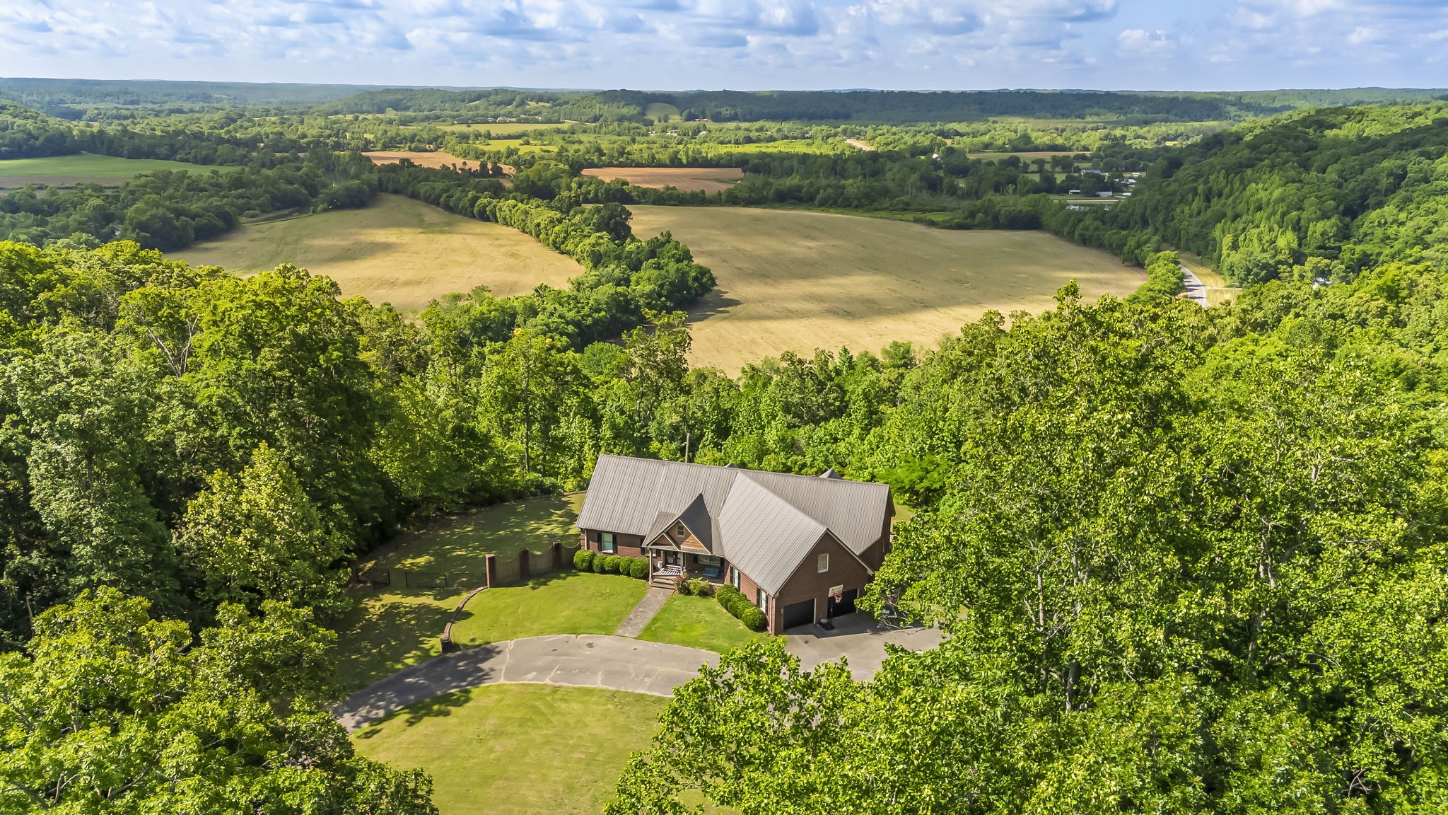 **Seller has accepted an offer with 24 hour first right of refusal contingency.** Perched high above the breathtaking Buffalo River Valley, this extraordinary 51+ acre estate offers the perfect blend of luxury, privacy, and natural beauty. Surrounded by mature hardwood forest and sweeping panoramic views, this remarkable property is a rare opportunity to own a true Tennessee retreat with convenient access to I-40 and an easy drive to Nashville.  The custom-built all-brick home was thoughtfully designed for both everyday living and unforgettable entertaining. The spacious main level features a private primary suite along with three additional bedrooms, creating an ideal layout for families of all sizes. Expansive living spaces are filled with natural light and positioned to capture the stunning surrounding scenery.  The fully finished daylight basement opens directly to the resort-style inground pool and offers incredible additional living space, including two more bedrooms, a dedicated craft room, a private home theater, and an oversized workout area. Whether hosting large gatherings, accommodating guests, or creating the ultimate multi-generational setup, this home delivers unmatched flexibility and comfort.  Step outside and enjoy the peaceful setting, abundant wildlife, and the tranquility that only a property of this size can provide. The gently rolling wooded acreage offers endless possibilities for recreation, hiking, hunting, ATV trails, or simply enjoying the privacy and serenity of the countryside.  Properties combining this level of craftsmanship, acreage, scenic beauty, and accessibility are increasingly difficult to find. From the stunning valley views to the thoughtfully designed living spaces and outdoor amenities, every aspect of this property was created to embrace the best of Tennessee living.  A rare opportunity to own a premier private estate overlooking one of Middle Tennessee’s most scenic river valleys.
