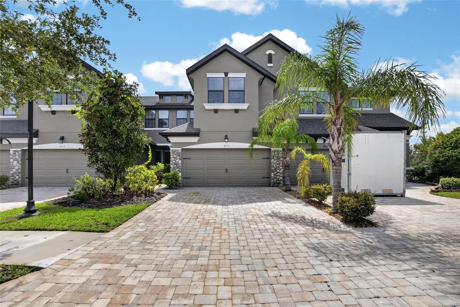 Welcome to maintenance-free living in this beautifully upgraded 3-bedroom, 2.5-bath townhome located in a desirable gated community in Wesley Chapel!This move-in ready home features a 2-car garage, paver driveway and walkway, covered front porch, stone exterior accents, gutters, and mature landscaping that create outstanding curb appeal.Inside, the open-concept floor plan showcases wood-look tile flooring throughout the main living areas, designer lighting, recessed lighting, and a stylish accent wall in the spacious living room. The gourmet kitchen is the heart of the home with granite countertops, a large center island, elegant glass pendant chandelier, upgraded cabinetry with decorative trim and hardware, and a pull-down faucet—perfect for entertaining and everyday living.The staircase features beautiful wood and metal spindle railings leading to the second floor, where you'll find all three bedrooms. The spacious primary suite offers laminate flooring, a tray ceiling with recessed lighting and ceiling fan, and a luxurious ensuite bath complete with dual granite vanities, soaking tub, separate tiled walk-in shower with rainfall shower head, private water closet, and generous counter space. Secondary bedrooms feature comfortable carpeting and spacious oversized rooms that are welcoming.Enjoy Florida living year-round from the extended screened lanai, providing the perfect space for relaxing or entertaining.The HOA offers true low-maintenance living by including lawn and landscape maintenance along with exceptional community amenities including a gated entrance, resort-style pool, dog park, sidewalks throughout the neighborhood, mature trees, and beautifully maintained tropical landscaping.Located in the heart of Wesley Chapel, one of the Tampa Bay area's most sought-after communities, you'll enjoy convenient access to I-75, Tampa Premium Outlets, The Shops at Wiregrass, The Grove at Wesley Chapel, KRATE at The Grove, AdventHealth Center Ice, Wiregrass Sports Campus, top-rated hospitals, restaurants, entertainment, golf courses, and parks. Downtown Tampa, Tampa International Airport, MacDill Air Force Base, award-winning Gulf Coast beaches, and world-famous attractions including Busch Gardens, Adventure Island, Walt Disney World, Universal Orlando Resort, and SeaWorld Orlando are all within easy reach.This beautifully upgraded home combines stylish finishes, low-maintenance living, outstanding community amenities, and an unbeatable location—making it the perfect place to call home. Schedule your private showing today!