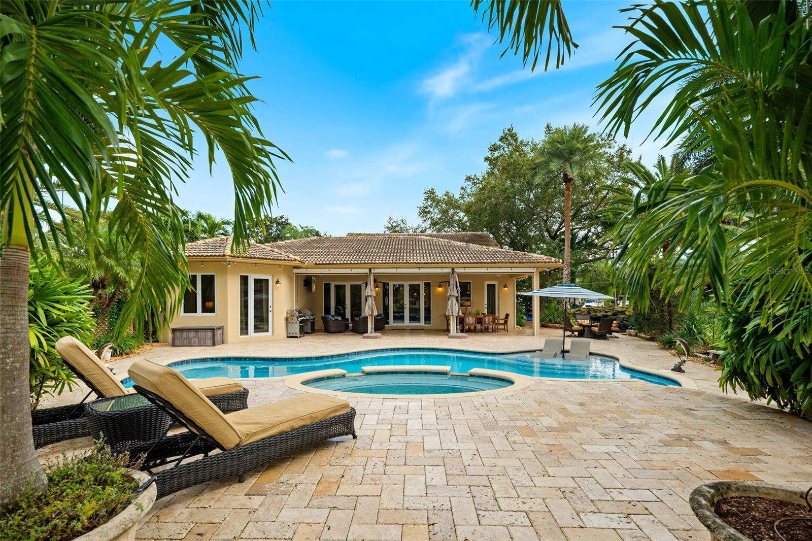 Welcome to 3800 SW 137th Ave, a distinguished private estate set on more than an acre in Miramar, where timeless design, exceptional privacy, and resort-inspired outdoor living come together in an extraordinary South Florida setting.Enclosed by a fully fenced perimeter and framed by lush, mature tropical landscaping, this impressive 5-bedroom, 3.5-bath residence offers a rare sense of space and seclusion along a tranquil canal. From the moment you enter, high ceilings, custom millwork, and beautifully crafted wood built-ins establish an atmosphere of understated elegance and refined comfort.At the heart of the home, the renovated kitchen is both sophisticated and inviting, appointed with striking quartzite countertops, elevated finishes, and generous workspace designed for effortless everyday living and elegant entertaining. A custom bar enhances the home’s entertaining appeal, creating a natural gathering place for intimate evenings or larger celebrations.The expansive primary suite is privately positioned on the main level, offering a serene retreat from the rest of the home. A second private suite upstairs provides exceptional flexibility for guests, extended family, or multigenerational living. A private den or executive home office, anchored by a wood-burning fireplace, brings warmth and character while providing an intimate space to work, read, or unwind.The outdoor living spaces rival those of a private resort. A covered patio outfitted with Phantom retractable screens creates a seamless extension of the interior living areas and allows for year-round enjoyment. Beyond, a heated saltwater pool and spa invite relaxed afternoons and elegant evenings beneath the South Florida sky. A tranquil koi pond with a cascading waterfall adds another layer of serenity, while expansive lawns, established landscaping, and peaceful canal views create a truly secluded backdrop.With more than an acre of fully fenced grounds, this exceptional residence offers a level of privacy, scale, and outdoor living rarely found in Miramar. Sophisticated yet welcoming, 3800 SW 137th Ave is a remarkable estate designed for gracious entertaining, relaxed luxury, and an elevated South Florida lifestyle.Professional photos will be available Sunday