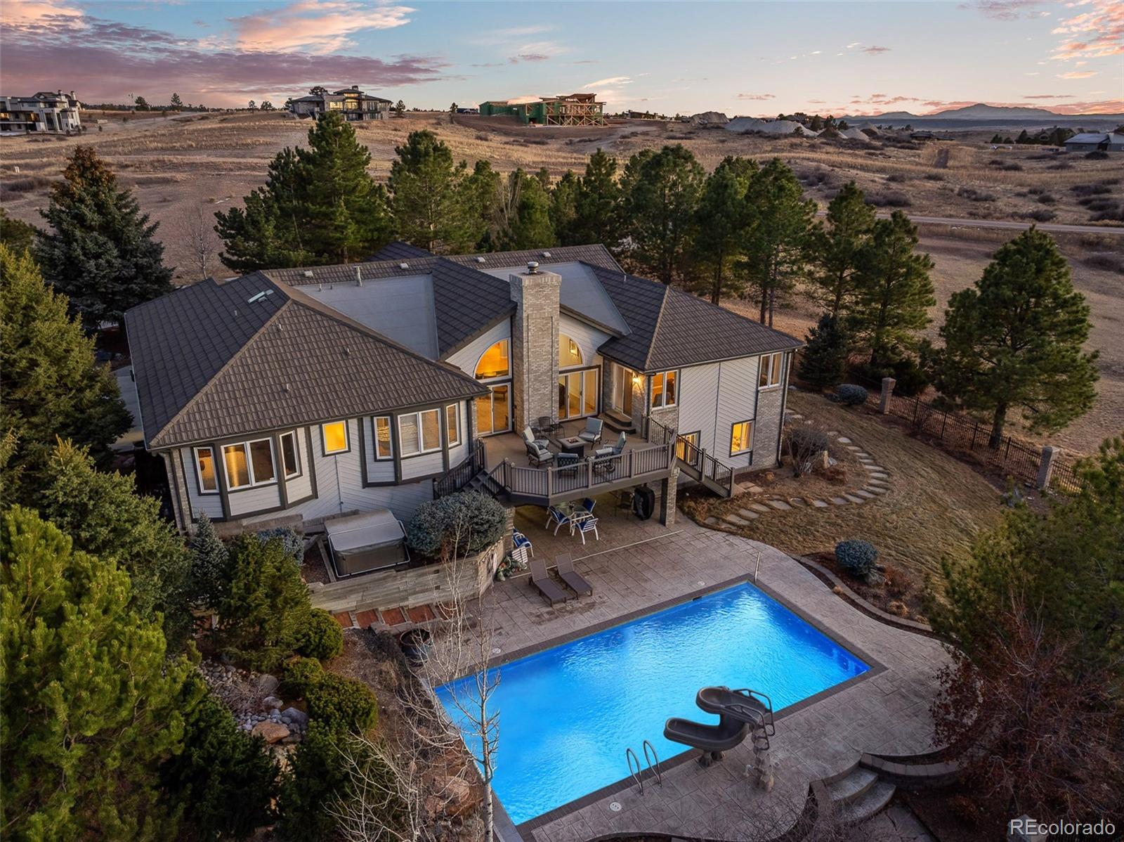 Set on five acres and backing to open space in the coveted Butterfield subdivision, 7539 Stroh Road delivers a resort-style experience with an exceptional balance of rural lifestyle and everyday convenience. Surrounded by mature pines and rolling landscape, this walk-out ranch offers the rare opportunity to own acreage, views, and long-term potential—just three miles from downtown Parker and directly across from the Colorado Golf Club.Outdoors, the property truly distinguishes itself. A resort-style in-ground pool and hot tub create a private retreat rarely found on acreage properties, complemented by multiple patios, decks, and seating areas designed for both quiet mornings and lively evenings. The layered outdoor spaces invite year-round enjoyment while preserving privacy and open views.With over 6,700 square feet, the home offers a sense of space rarely matched in this setting. Designed for true main-level living, the floorplan includes multiple bedrooms on the main floor, an executive office, and a layout that functions equally well for everyday living or entertaining. The kitchen—appointed with maple cabinetry and stained concrete countertops—provides a solid, functional foundation, offering the next owner the opportunity to personalize finishes while preserving the home’s thoughtful flow and scale.The walk-out lower level expands the home’s versatility, supporting multi-generational living, guest accommodations, or extended entertaining. Additional living spaces include wet bar and kitchenette areas, a dedicated gym, and a private lower-level suite, all with direct access to the outdoors—reinforcing the home’s strong connection to its natural setting.Opportunities like this—five acres backing to open space, minutes from town—do not come along often. Experience the setting, scale, and lifestyle of 7539 Stroh Road with a private showing.