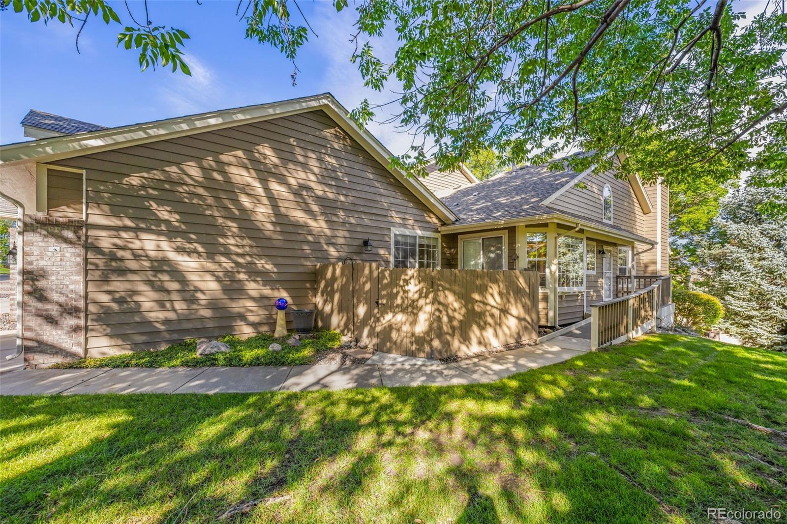 From the moment you arrive, this ranch-style end unit feels welcoming, open, and remarkably easy to live in. Fresh paint, classic real wood flooring, and large windows create a bright, open, family home feel with no cramped condo vibes.The setting is special. A playground is nearby, with trails and open space only a few blocks away. The community’s four ponds once irrigated the apple orchard that stood here, and gorgeous leafy trees still create a beautiful, established neighborhood today.The spacious living room centers around a classic brick fireplace, with white shutters adding both charm and privacy. Step outside to a peaceful patio, also accessible from the primary bedroom. The cheerful eat-in kitchen features slab granite countertops, tile backsplash, and newer stainless appliances, with a second fenced patio just outside—perfect for grilling, outdoor dining, or for your 4 legged friends to sun themselves while you relax.One of the home’s most distinctive features is its thoughtful ADA and customized wheelchair accessibility. Ramped entrances at both the front door and attached garage provide easy access, while the main-level primary suite features a wide entry and accessible en suite bath—hard-to-find features that offer flexibility for a variety of needs.An additional bedroom with new carpet on the main features a full bath next door and extra space for an office or guests. The finished basement has fresh paint and new carpet/pad. It offers a large family room, additional bedroom, full bath, additional storage, and roomy laundry area with washer and dryer included. The family room even opens to a third patio!Enjoy the community pool and clubhouse with your guests, mature landscaping without the yard work, an attached garage, end-unit location, and three outdoor living spaces. It’s a rare combination of space, accessibility, character, and the simplicity of low-maintenance living—all in popular Brittany Terrace.