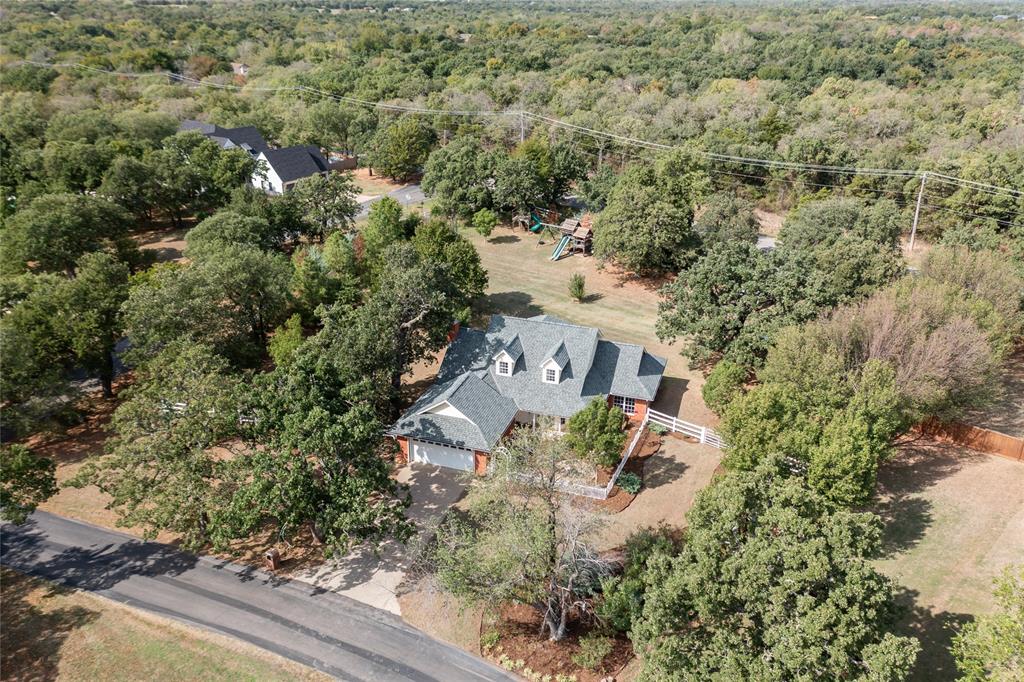 Edmond public schools, but Logan County taxes, and no water bill?? YES please!Plus fresh eggs, front porch mornings and a little kayaking after dinner? This is the kind of place you settle into and homes in this small community rarely come available.Set on 1 fully fenced acre with mature trees, this remodeled home offers Edmond schools, lower Logan County taxes, OKC utilities and no water bill thanks to a private well and septic system. New lateral lines and a new well pump are already checked off the list! A charming courtyard with flagstone pathways and a bird bath welcomes you in. Inside, wood-look tile, leathered marble countertops, a fireplace, built-ins and a wet bar make it easy to feel at home. The updated kitchen features stainless steel appliances, an induction cooktop, Bosch dishwasher, double ovens and a walk-in pantry and the refrigerator stays! The downstairs primary suite includes two closets, double vanities, a soaking tub and an updated walk-in shower. A light-filled study/flex space gives you room to work or unwind, while the covered front porch and freshly painted back deck invite you to stay awhile. Bring the horses, chickens and weekend projects! The workshop/barn offers stall space for up to two horses, electricity, an overhead door and a tack/work area with a concrete slab. A custom greenhouse/chicken coop and in-ground garage storm shelter add to the appeal. And then there’s the neighborhood’s private 40-acre lake for fishing, kayaking and small-engine boating. Room to breathe, room to play and a little country living without giving up modern comforts. Come see what makes this community so hard to leave.