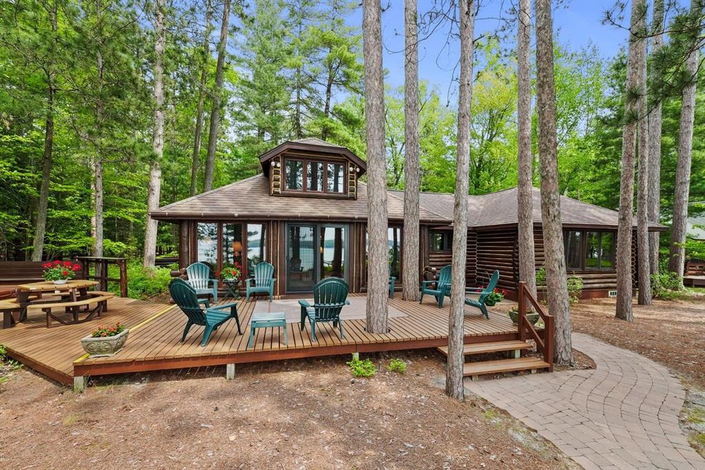 A Rare Opportunity on Higgins Lake's East Shore! Step into timeless charm and natural beauty with this historic 1929 whole log home, beautifully maintained and showcased on a 114' x 245' pine-wooded lot along the east shore of Higgins Lake. With 114 feet of sandy beach and shallow, swimmer-friendly water, this lakeside retreat offers panoramic lake views with stunning sunset experiences! The cozy yet spacious log interior is perfectly chinked and impeccably preserved, featuring an original stone wood-burning fireplace and a lake-facing wall of windows that fill the space with light and lake views. The home sleeps up to 10 guests comfortably, with 3 bedrooms, a den with a hide-a-bed, and a loft for extra sleeping space. You will enjoy 1/7 ownership interest in the historical Flag Point Club with amenities including tennis and pickle ball court, a carriage house with storage, and a guest house- that is available for reservation when you need space for additional company. Enjoy expansive outdoors living with a large lakeside deck, hot tub, and multiple seating areas ideal for entertaining or unwinding with a book. Whether you're looking for a vacation home, family retreat, or rare piece of Michigan history, this lakeside log home delivers character, comfort, and unforgettable views of the most beautiful lake in Michigan. Welcome to Pine Cone Cabin!