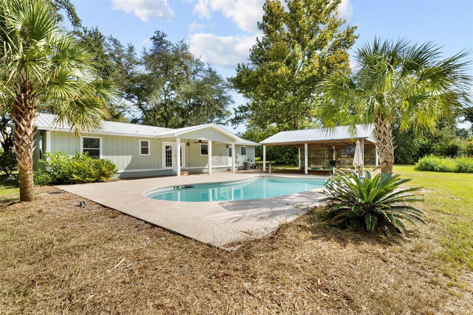 Completely remodeled 3 bedroom/2 bathroom ranch style house on 18 gorgeous acres with a POOL in Gilchrist County. Talk about a find! This property is a dream. Travel down the long private driveway covered with grandaddy oak trees, you will arrive at this beautiful home tucked deep into the trees. The two front pastures have been used for hay but would be ideal for horses, cows ,crops and more. The property is full of fruit trees, loquat, fig, citrus and muscadine grapes. This gorgeous home has a metal roof, all new painting inside and out. You will love the bright open floor plan, all brand new flooring throughout the whole home. Nice calm color scheme, gorgeous kitchen with brand new cabinets, granite countertops and appliances. Dining room offers French doors that lead to the back patio with a gorgeous view of the in ground pool. Living room is nice and open with a nostalgic wood stove. A true split floor plan with 2 spacious guest bedrooms and guest bathroom with brand new dual vanities and a combo tub/shower. Master bedroom is oversized with dual closets and a brand new bathroom with dual vanities and walk in shower. Laundry room is nice and spacious with brand new hot water heater and exit door to the back patio. Out back you have a detached pole barn perfect for parking your vehicles and/or atv's. A multi stall barn perfect for parking the tractor, storing items or for animals and a shed perfect for storage. This property has so much to offer and with all the major updates makes this home more than move in ready. Own a little slice of Florida , what better way to enjoy the quiet countryside with 18 gorgeous acres and a pool? Call today for YOUR tour!