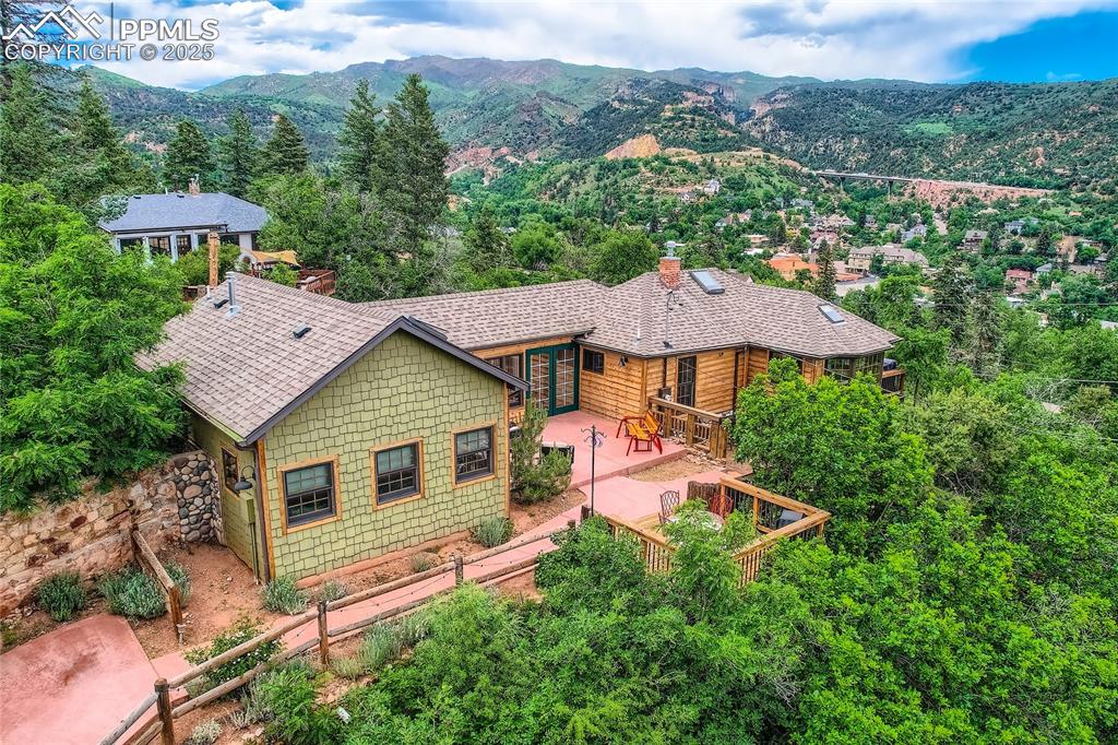Nestled in the scenic hills of historic Manitou Springs, this stunning mountain chalet offers a rare blend of charm, comfort, and BREATHTAKING VIEWS! You’ll be captivated by the natural beauty surrounding this home, w/vistas of the city, the iconic cliff dwellings, & the majestic Garden of the Gods. This ranch-style home w/walk-out basement is designed to impress. The living room and office boast beamed wood ceilings which adds character & warmth, complemented by gleaming wood floors & skylights that flood the space w/natural sunshine. It won't be difficult to work from home in this office w/ built-in desk & views from the many windows.  The home’s rustic appeal, while the thoughtful touches inside and out make it truly one-of-a-kind. The front of the home has AC and ceiling fans are present throughout the home ensure year-round comfort.  An addl gas stove in the LR keeps in cozy in the winter.  With 2 master suites, each featuring its own private bath, this home offers unparalleled class & privacy. The primary walk-thru closet is w/custom shelves provides both style & functionality w/ensuite full bath.  The 2nd master is located on the lower floor w/walk-in closet & cabintry & a walkout to a private covered stone-paved patio.  Behind barn doors, you will find more custom closets in the foyer which add a classy, practical addition.  Start your morning w/a view from one of the home’s many decks.  This property features several outdoor spaces, each offering stunning views & a connection to the natural habitat landscaping that surrounds the home. Stone walls, red concrete driveway lead you to an oversized 2 car garage complete w/a split system for air conditioning & heat, making it a versatile space for hobbies, storage, or a workshop. This home is more than just a place to live—it’s a retreat, a sanctuary, and a gateway to the best of Colorado living. Don’t miss your chance to own this exceptional property in one of the most sought-after locations in Manitou Springs!