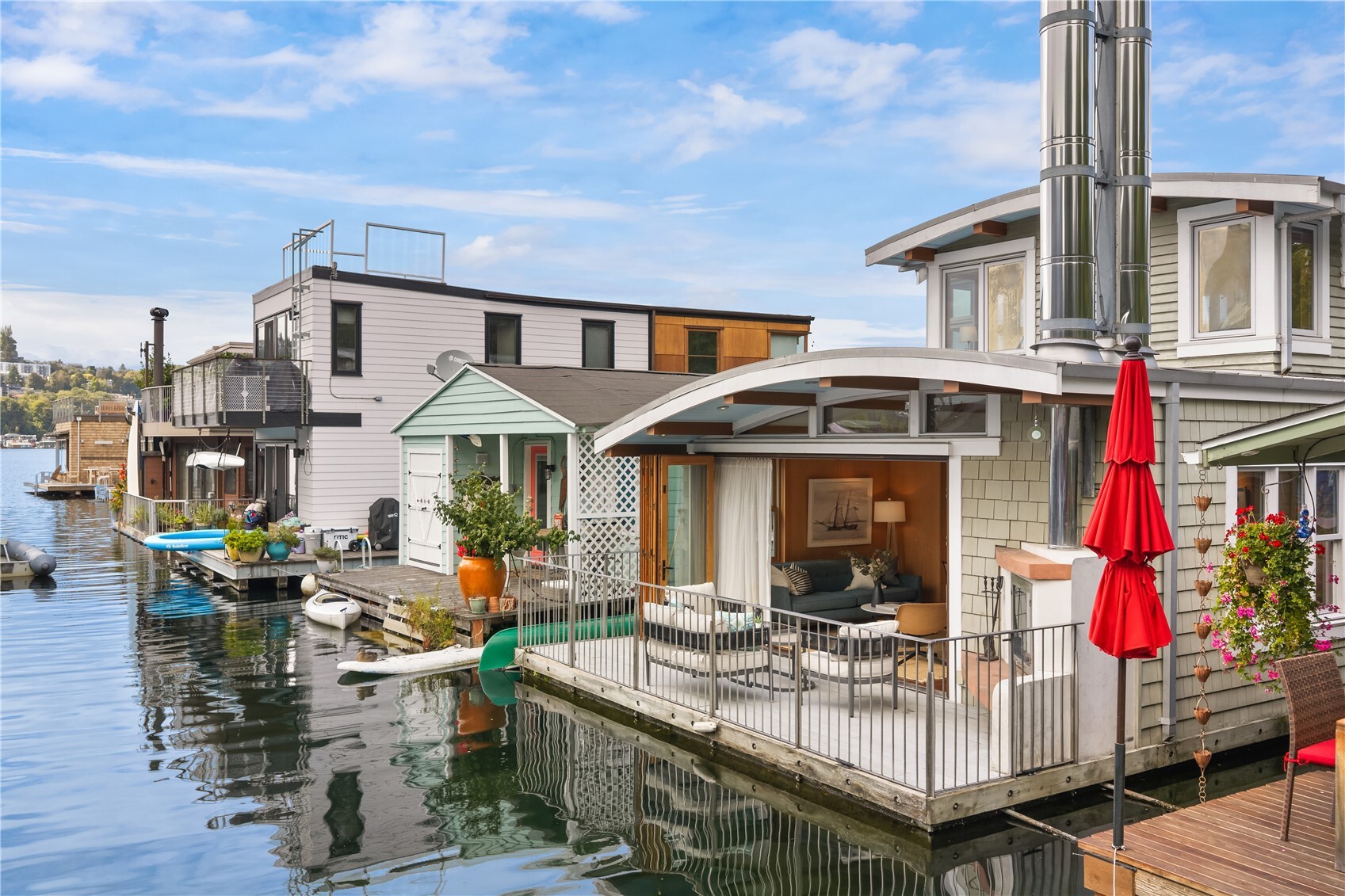 A cheerful white pergola welcomes you onto the dock at Tenas Chuck — dockside living unlike any other. This sunny south-facing floating home was re-imagined in 2004, and rebuilt to embrace history while elevating modern dockside living. A sprung roof over cedar shake siding, a rooftop deck with cable railings, a chambered concrete float — from the dock, a timeless silhouette that belongs on the water. Inside a NanaWall accordion glass door opens the great room entirely to the waterside deck, dissolving interior and exterior lines. Two back-to-back fireplaces (gas or wood) serve both interior and deck. The outdoor masonry fireplace doubles as a grill, adding activity and joy to every season. The kitchen is built for cooking & entertaining: DCS range, Subzero refrigerator, Fisher & Paykel dish drawers. Anigre-paneled walls with custom art hangers, cove lighting, heated floors, and whole-house audio wiring give the interior a warm, modern, considered feel. Custom-tiled jetted tub and extensive built-in storage throughout. Includes small boat & paddleboard moorage on 3 sides. Eastlake's Tenas Chuck Moorage is a registered historic floating home community with nearby parking and EV charging available. Steps from Eastlake's Smallest Floating Home Museum, shops, groceries, and restaurants. And when the Fourth of July arrives, you already have the best seat in Seattle. Come join us on the lake!