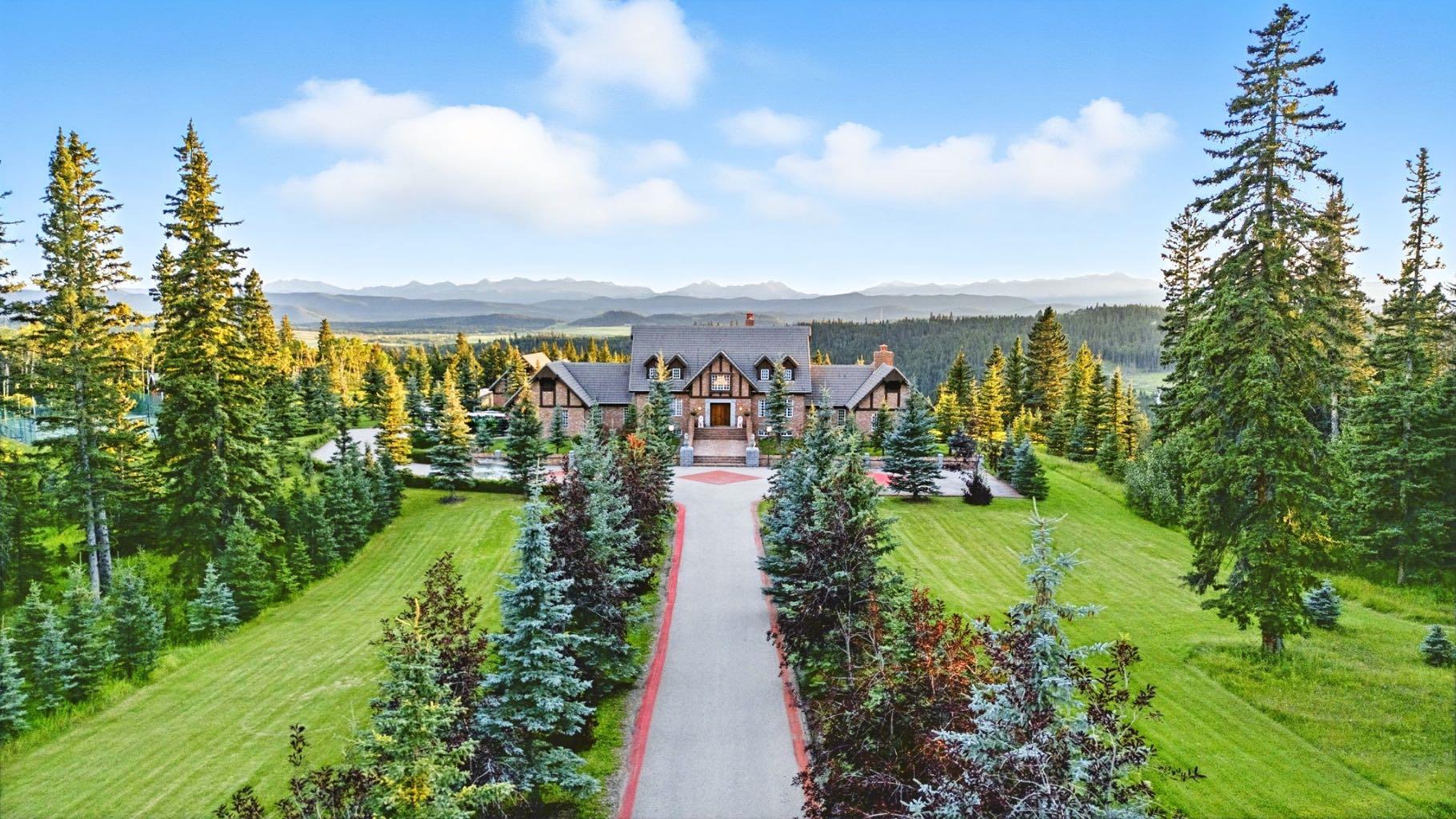 This is a rare and exceptional opportunity to own a 192-acre estate in the highly sought-after Millarville area. Perched at an elevation of 5,000 feet, this extraordinary property offers breathtaking mountain views and an array of premium amenities. At its heart lies a custom-built, European-style two-story residence, thoughtfully designed for both luxury living and recreation. Spanning over 8,000 sq. ft., the stately brick residence features seven bedrooms and 6/2 bathrooms, including five en-suites. The home offers a formal study, an elegant dining room, a main-floor primary suite (with an additional primary suite on the second level), and private nanny quarters. A stunning sunroom with floor-to-ceiling windows provides an idyllic space to take in the breathtaking views of the pool and Rocky Mountains. Meticulously crafted with exceptional detail, the home showcases custom hand-carved woodwork, coffered ceilings, four fireplaces (one wood-burning and three gas), and a combination of hardwood and custom tile flooring. Italian marble finishes add a touch of sophistication to most bathrooms. The chef’s kitchen, features an open-concept layout with beamed ceilings, a unique brick island and dining table, a rare AGA range and high-end built-in appliances blend seamlessly with the custom cabinetry. The main-floor primary suite is a true retreat, boasting a grand gas fireplace, spectacular mountain views, and an opulent ensuite with separate his-and-her bathrooms, walk-in closets, dual showers, and a stunning clawfoot tub as the centrepiece. The estate features a 4-season 24x80 heated outdoor saltwater pool enclosed within a custom glass structure. This impressive pool—measuring four meters at its deepest point—includes a 10-foot diving board, a slide, and panoramic 180-degree mountain views. Heated flooring surrounds the pool area, while a beautifully designed pergola provides the perfect space for entertaining. Adjacent to the pool, the pool house offers added convenience, complete with a kitchenette, a loft, washer/dryer, a/c, and a bathroom featuring a steam shower. For sporting enthusiasts, the property boasts world-class shooting facilities, including: Rifle ranges, Skeet shooting range, Olympic double shooting range, Rabbit clay setup, High sporting clay doubles and mini doubles. Dirt bike riders will appreciate the professionally designed 2-3 km motocross track, featuring 60-80 jumps at the northern end of the property, or Equestrian enthusiasts can use this 20 acres of open fields, for grazing. Nearby, a 1-2 acre pond—equipped with aerators and stocked with 800 trout—adds to the property’s natural beauty. Additionally the Estates features include a Tennis court, a 40x20 carriage house (easily convertible into a barn with dutch doors) with an upstairs man cave, a 80x30 quonset, and a Charming 300 sq. ft. log cabin with loft and wood-burning fireplace. This one-of-a-kind property must be seen to be truly appreciated.
