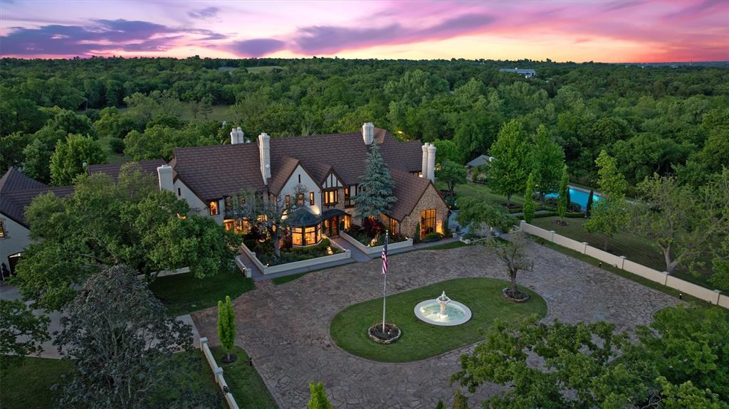 2203 E Wilshire Boulevard is a property of extraordinary provenance and architectural distinction.  This gated 12.4-acre estate is one of Oklahoma City's most revered legacy homes, where timeless Tudor elegance meets curated modern luxury. Meticulously reimagined yet historically preserved, this is not simply a residence, it’s a private sanctuary built to transcend generations. Nestled beneath a canopy of mature trees at the end of a stone-lined drive, the stately main house commands attention with its gabled rooflines, turreted entry, and richly appointed façade. Once inside, a world of bespoke craftsmanship unfolds, restored barrel-vaulted ceilings in hand-carved wood, a monumental Italian limestone fireplace, and original millwork that tells the story of a home shaped by time and refined by vision. A custom-designed kitchen by Karen Black of Kitchens by Design, is a masterpiece of form and function. The estate’s living spaces are as memorable as they are inviting. A warm, wood-paneled library evokes the charm of an English countryside manor, while formal and informal living areas invite gathering and reflection, bathed in natural light and garden views. Five fireplaces throughout offer comfort and ambiance in every season. Outdoors, the amenities rival those of a private resort. A 90,000 gallon pool anchors the grounds, flanked by a full-service kitchen cabana clad in custom stainless cabinetry. The climate-controlled swim spa with retractable nano walls creates a seamless indoor-outdoor experience year-round. Adjacent are a lighted tennis court, a stocked pond with a dramatic fountain, and expansive lawns ideal for events, play, or pastoral escape. Equestrian-ready, the property features two stables, a tack room, and perimeter electric fencing. Two private wells support the home, pool, and irrigation, while modern infrastructure, including a whole-home generator, an elevator to all three levels, a wine cellar, and a five-car garage, ensure effortless living.