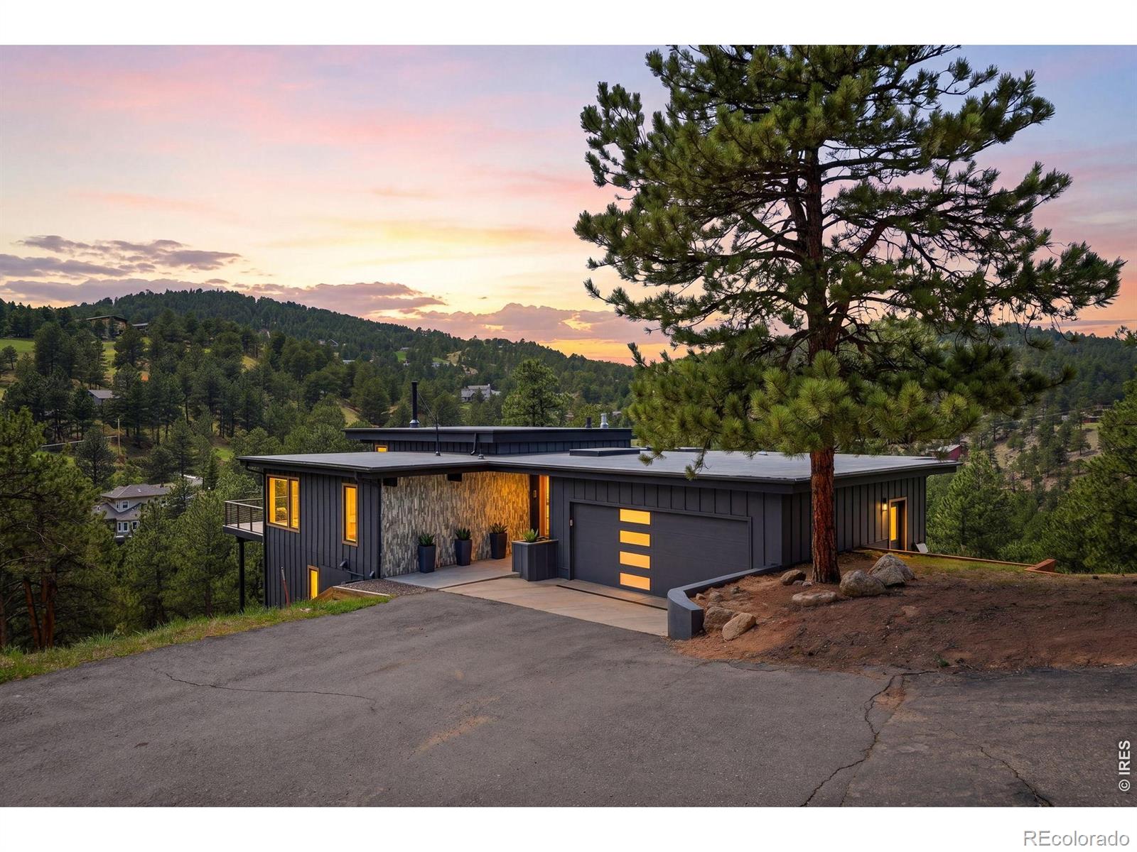 Reimagined and completely remodeled in 2022, this striking Mountain Modern home blends bold architectural style with seamless indoor-outdoor living. Dramatic floor-to-ceiling windows and skylights flood the open floor plan with natural light while framing serene mountain, forest, and lake views. This unique 4.75-acre property is one of the largest and most private in Pine Brook Hills. New wraparound decks and a covered outdoor living room create inviting gathering spaces. The open living space features 11-foot ceilings, hickory wood floors, oversized windows, and a reclaimed barn wood framed fireplace that anchors the home with warmth and character. Enjoy cooking in the contemporary kitchen with quartz countertops, SS appliances, a large custom pantry, and a coffee station. This home lives like a custom new build. There is a new garage, new heating and A/C systems, new Marvin Vivid Collection windows and sliding doors throughout, new exterior siding, and upgraded insulation. They literally raised the roof to create a striking contemporary roofline. A stylish entry, foyer, bathroom and mudroom with storage for coats, shoes and gear were added in 2022. On the main level you'll find a spacious and bright bedroom suite ideal for single-level living with a walk-in closet and en suite bathroom, as well as a large flex room that can serve as a family room, office, or 4th bedroom. The lower level includes a private primary suite with separate his and hers closets, a luxurious 5-piece bathroom with freestanding soaking tub, beautifully tiled shower with dual shower heads, and double vanity sinks. A private deck is perfect for morning coffee or a future hot tub. Pine Brook Hills offers a rare blend of privacy and natural beauty just 10 minutes from dining and shopping on Pearl Street Mall. Enjoy hiking in the morning and the Sundance Film Festival in the afternoon. Award-winning K-12 BVSD schools. Property is Wildfire Partners Certified and insurable with Allstate.