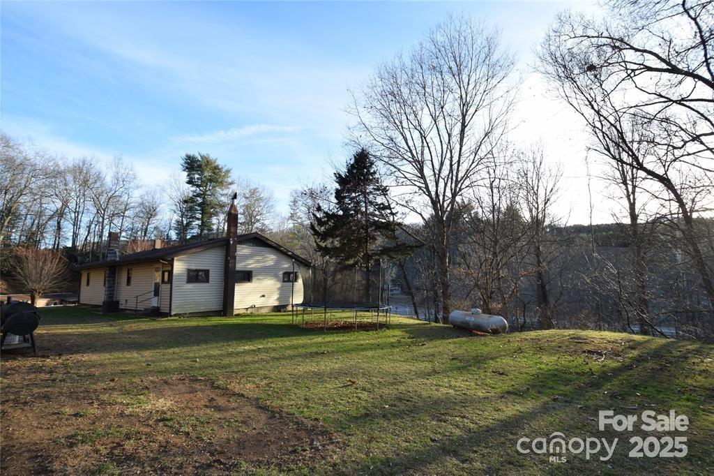 Lease with the option to buy! Great location in East Burnsville with easy access off Hwy 19! Sweet home built in 1970 sits on 4 mostly wooded acres! At the top of the property is a beautiful potential home site with huge views towards Mt. Mitchell. House boasts all main level living and is wheel chair accessible with a solid ramp to the front door. Open living room and kitchen with lots of sunlight. Large hallway runs the length of the house from the smaller bedroom to the larger bedroom that has a private full bath. Second full bath in the hallway with washer dryer hookups. The canning kitchen / enclosed back porch offers additional storage with pantry & closet. Large side yard has plenty of room for a garden & play area for kids. Wood barn/ shed + small metal shed. Beyond the yard the path goes up the mountain to the back/ top side of the property. It’s a fantastic hike up the mountain with beautiful winter views thru the mature tree growth. All you need is a road & you could build an amazing home at the top!