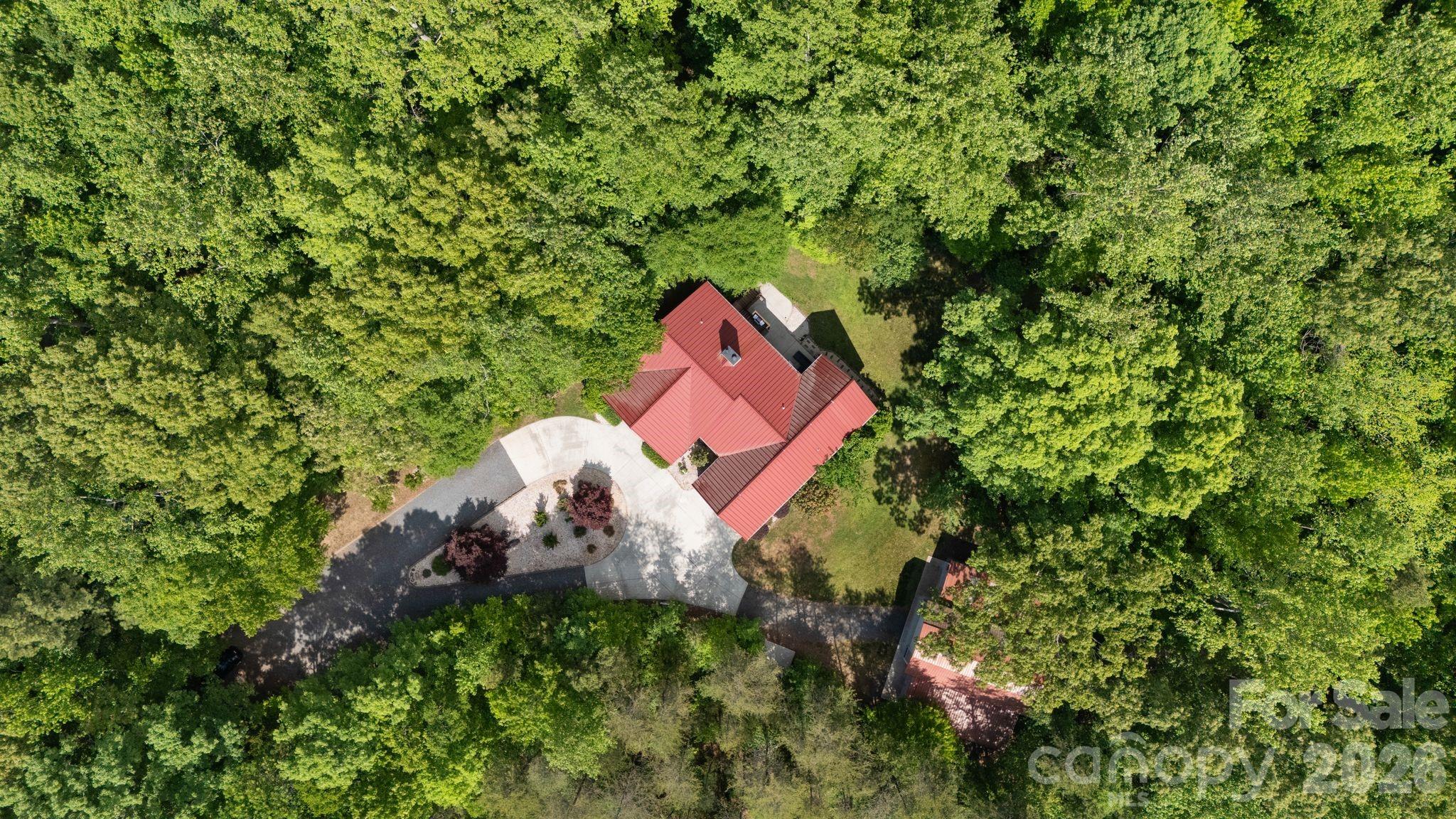 A RARE opportunity to own a private country estate on nearly 8 acres featuring PROTECTED LAND around your estate giving you unmatched PRIVACY, peace pace but close to conveniences and top-rated schools, and land curated amenities—from trails, axe-throwing, parking lot, guest parking area, circular entrance with TWO DRIVEWAYS (rarity!!!) & usability of acreage that's TURN KEY. Built in 2014, this custom home offers exceptional craftsmanship, much of which was curated from the land itself....truly one-of-a-kind that is an EXPERIENCE to see!This property is designed for both everyday luxury living to feel peace without sacrificing being too far away from everything.You CAN have it all at this RETREAT. Newly updated kitchen, tankless hot water heater, and a basement to impress with a: movie area, kitchen, game room, exercise room with sauna, office, and flex room being used as a 4th BEDROOM, and a utility room with an added sink....every room has been purposefully designed. Do not miss the CHARACTER this home speaks indoors and outdoors!Land complete with: so many trails, a sports field, fire pit, zipline, tree fort, swing, axe throwing area, parking lot, and a oversized barn with 14 ft doors to accommodate an RV or boat—creating a unique, resort-style experience right in your own backyard. Entry to property: featuring TWO separate entry points/driveways—an incredibly RARE and highly desirable feature that is very hard to get approved; along with ample parking spaces.Basement Level:Designed for entertainment and function, the lower level features a theatre area, gym, bar, kitchenette, two additional rooms, a full bath(built for a shelter), gas fireplace, and a mechanical room equipped with a tankless gas water heater and utility sink. Enjoy direct access to a covered patio, perfect for relaxing outdoors with string lights and speakers to enjoy your endless view whether its the wilderness or your large party or event outdoors.Main Level:The main level features an open and inviting layout with a vaulted ceiling living room and gas fireplace, spacious dining area, and a beautifully UPDATED kitchen equipped with a gas cooktop, pot filler, oversized commercial-grade refrigerator and freezer, dual sinks, large island with seating, extra prep sink, and a walk-in pantry with built-ins. The primary suite offers a private retreat with a full bathroom, walk-in luxury shower, and two separate walk-in closets. The primary suite wakes you up to sunrise through the windows that make you feel like you are in the trees. It's a pure escape and retreat! Two additional bedrooms are also located on the main level, each with access to their own full bathrooms on the opposite side of the house as the primary. Additional highlights include a mudroom, laundry room with sink, half bath, and an oversized 2-car garage with vaulted ceiling and the third floor flex room used as a bonus/yoga room.Enjoy outdoor living with both a covered wide front porch and a covered rear porch with stairs down to the back patio connected to the basement back door and entertainment space; perfect for taking in the peaceful surroundings or having a lavish party.The property also includes: a 2-car attached garage PLUS an approximately 1,800 SF detached 6-car garage/workshop with 14’ doors, ideal for RV or boat storage, hobbies, or additional workspace. HIGH SPEED INTERNET, 400A electrical to home and 1G internet. 60 YEAR METAL ROOF. Despite its private setting, the home is conveniently located just 4 miles from shopping and dining, including Lowe’s, Publix, and Walmart, 7 minutes to the Clover Recreation Center, and approximately 30 minutes to Charlotte Douglas International Airport, all within the award-winning Clover School District.