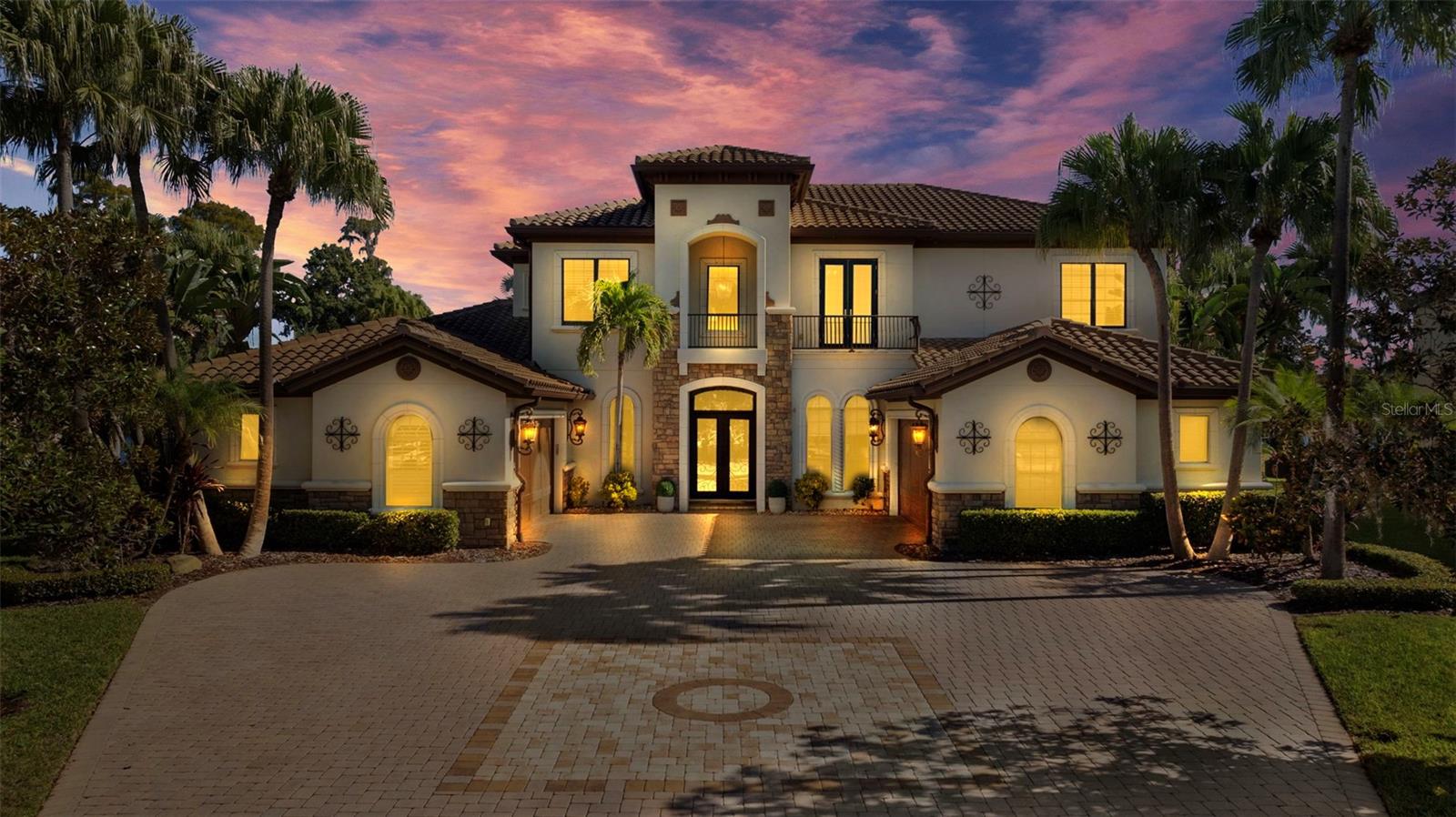 This beautiful lakefront home is truly one of the standout properties in all of North Tampa. Sitting on a private lakefront lot with over 300 feet of shoreline, it offers a peaceful, private setting that feels like your own personal retreat. Behind the gates, the home was custom built with care, combining classic craftsmanship with the kind of amenities you’d expect at a luxury resort. When you walk in, the home immediately welcomes you with its grand two-story foyer. Sunlight pours in through a huge picture window, giving you an instant view of the lake. Rich wood floors, detailed trim, tray ceilings, designer lighting, and a gorgeous wrought-iron staircase all set the tone for a home that is elegant yet inviting. A beautiful stone fireplace adds warmth and charm to the main living area. The kitchen is truly a chef’s dream. It’s designed for people who love to cook or entertain with two Wolf ranges, Sub-Zero refrigeration, Fisher & Paykel dish drawers, custom cabinetry, and a hidden walk-in pantry that even includes a wine fridge. The kitchen opens right into the living space, and brand-new 10-foot impact glass sliders fold open to bring the outside in. Step outside and you’ll feel like you’ve entered your own private resort. The 12-foot-deep, gas-heated pool features a rock waterfall, spa, sun shelf, swim-up table, and even cooling misters for hot days. Tropical landscaping surrounds you, and the lake creates the perfect backdrop. The covered lanai includes an outdoor kitchen, a cozy gas fireplace, and a dedicated pool bath that features both a sauna and a steam shower perfect for relaxing or entertaining friends and family. Upstairs, the large game and media room is designed for fun. It includes a built-in bar, multiple TVs, a new projector and screen, a gas fireplace, and a private balcony overlooking the pool and lake. A spiral staircase connects the balcony to the backyard so the fun can flow indoors or out. The primary suite feels like a peaceful getaway. Oversized bay windows give you sweeping lake views, and a double-sided gas fireplace adds a romantic touch. The spa-style bathroom includes marble finishes, dual vanities, a soaking tub, and an oversized shower with four shower heads. All of the additional bedrooms come with private bathrooms and walk-in closets, making them comfortable for family or guests. The home also includes a spacious office with French doors for anyone working from home. Important improvements have already been taken care of for you, including a 2020 roof, whole-house surround sound, new exterior lighting, two newer pool pumps, plantation shutters, detailed millwork, and a full security camera system that stays with the home. With unmatched craftsmanship, thoughtful features, and a one-of-a-kind lakefront setting, this home offers a luxury lifestyle that’s both elegant and truly comfortable. It’s a place meant to be enjoyed and cherished for many years to come.